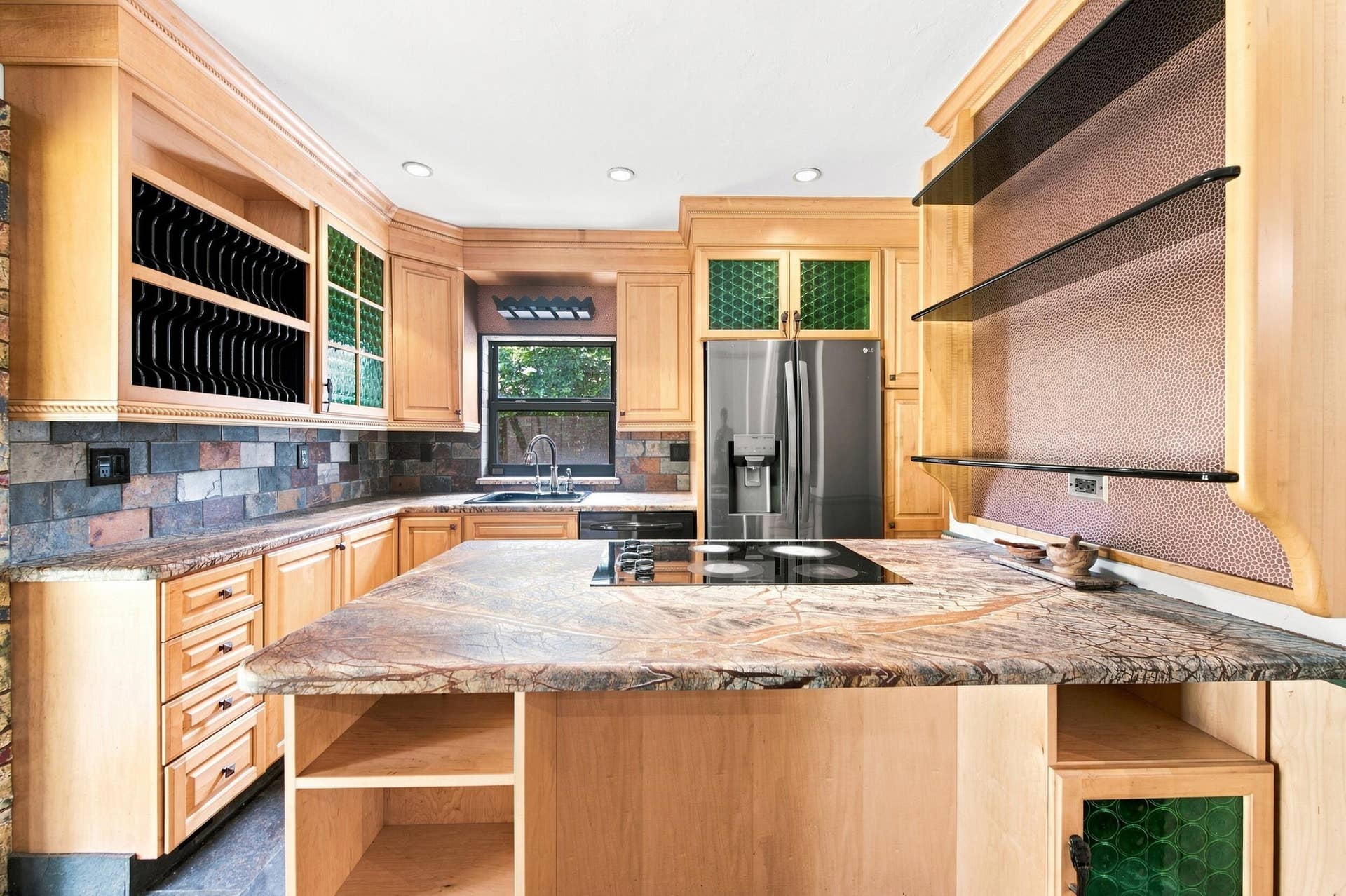 1110 SW 18TH Court, Fort Lauderdale, FL 33315 Chef's kitchen featuring custom wood cabinetry with glass-front upper cabinets, a large center island with stone countertop, stainless steel appliances including a French-door refrigerator, tile backsplash, and abundant recessed lighting throughout