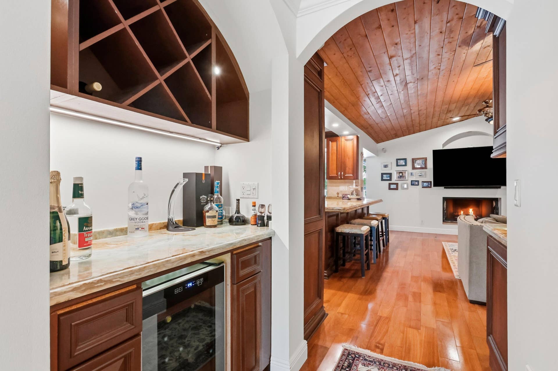 2919 Banyan Blvd Circle NW, Boca Raton, FL 33431 Wet bar featuring built-in cabinetry, arched wine storage, and an under-counter beverage refrigerator, highlighted by wood-finish flooring and a barrel-vaulted wood-paneled ceiling
