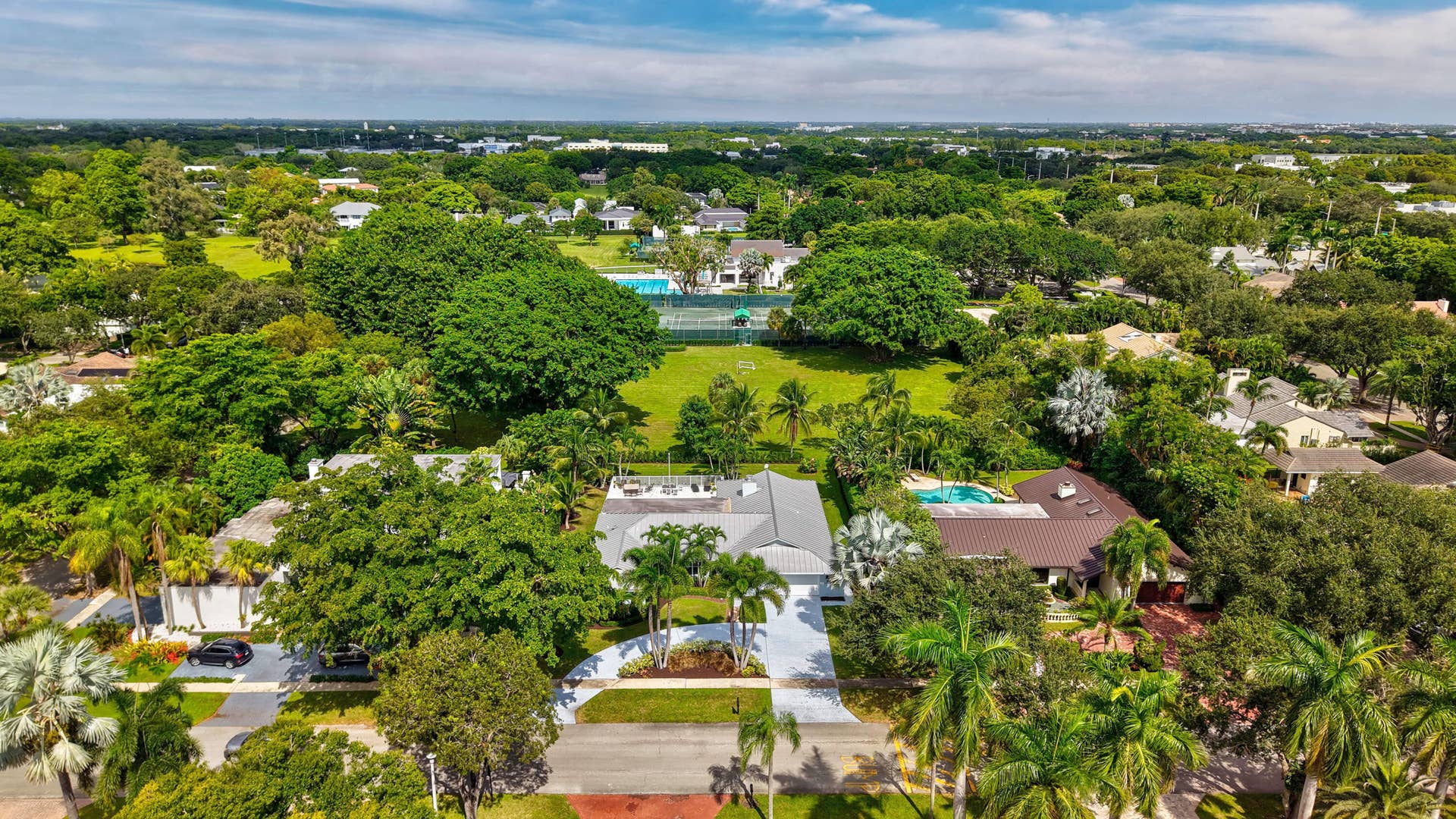 2919 Banyan Blvd Circle NW, Boca Raton, FL 33431 Aerial perspective of a sprawling property featuring mature canopy trees, expansive lawn space, and a private swimming pool with a screened enclosure