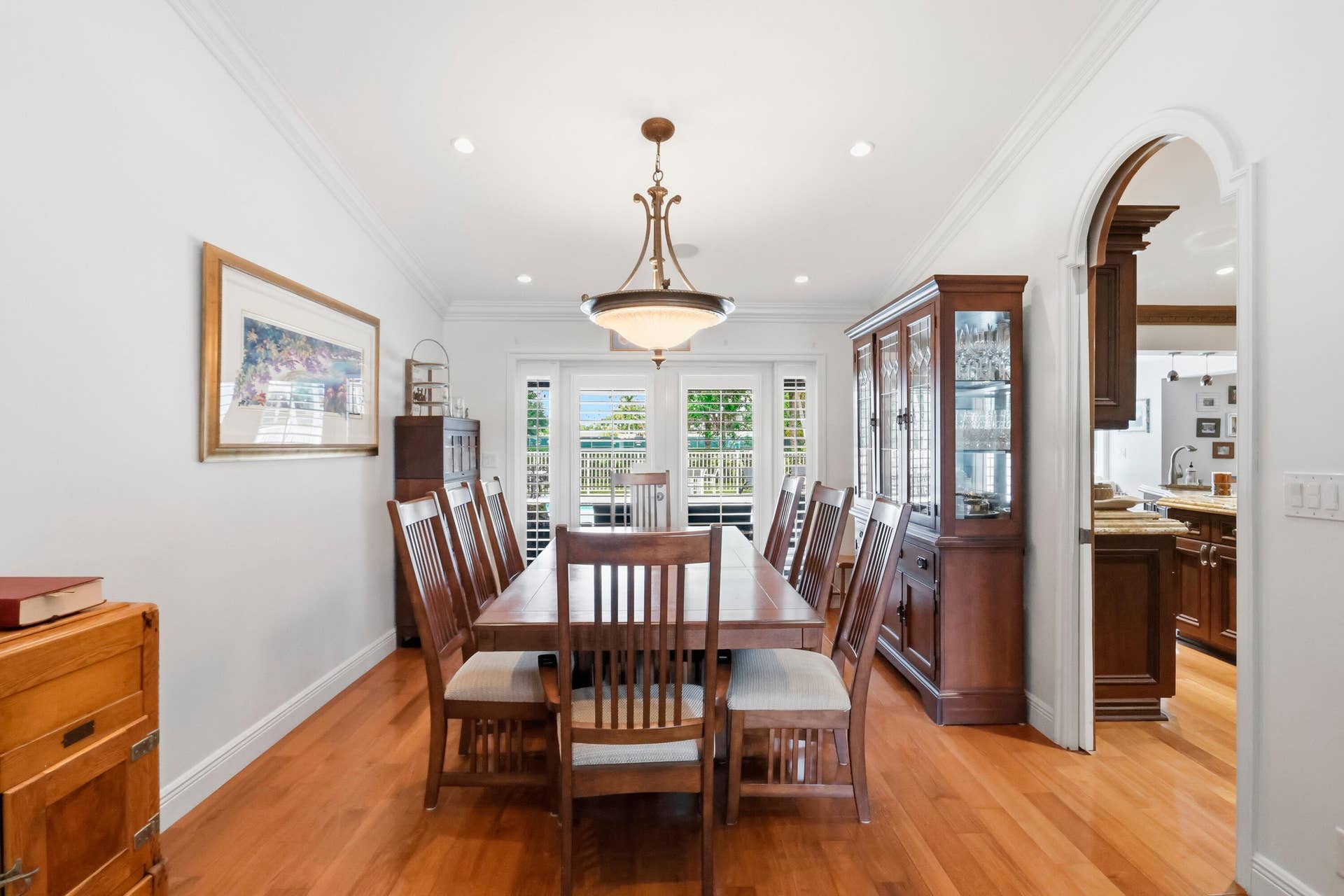 2919 Banyan Blvd Circle NW, Boca Raton, FL 33431 Dining area featuring wood-finish flooring, crown molding, recessed lighting, a central pendant fixture, and an arched doorway