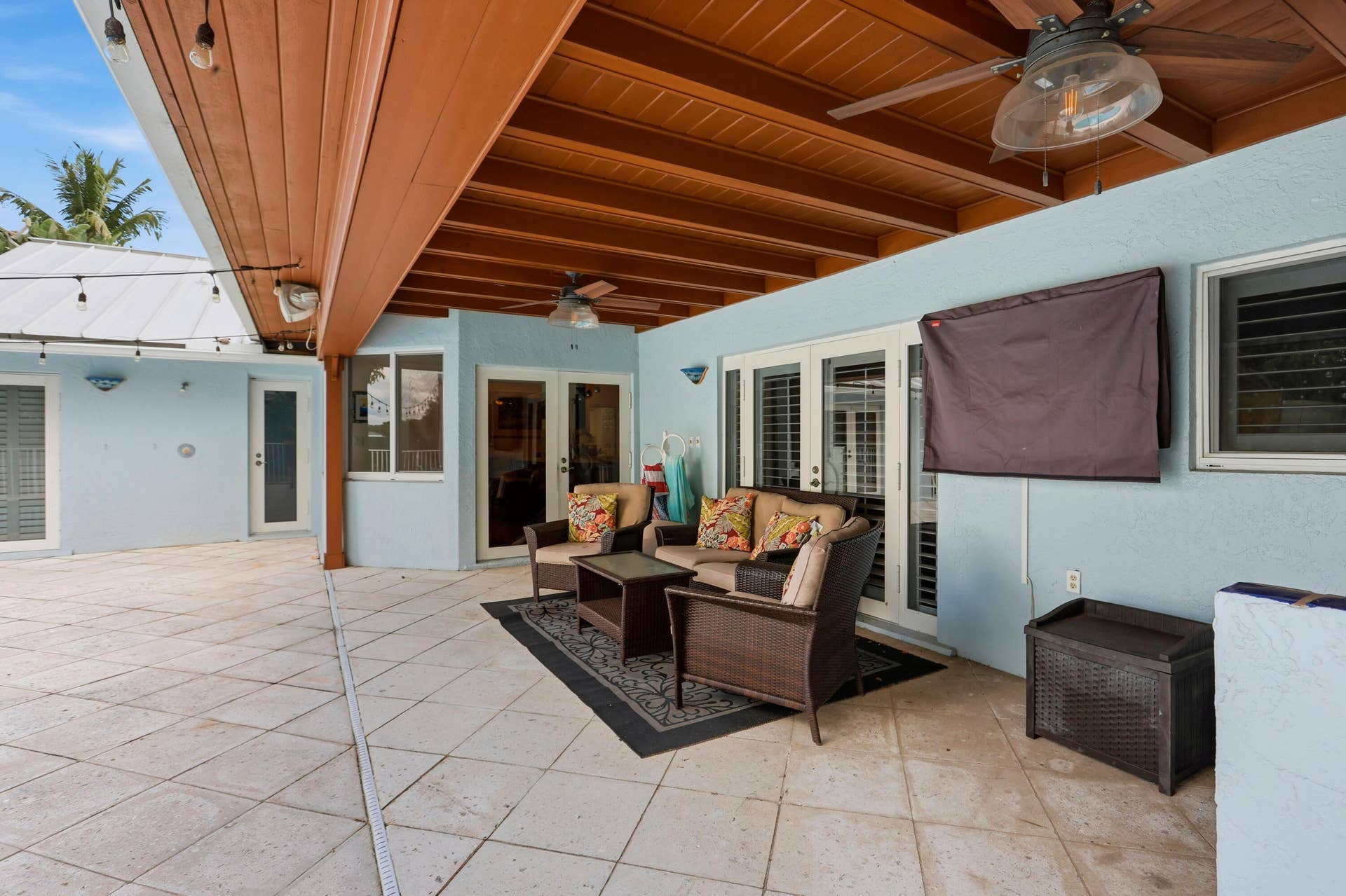 2919 Banyan Blvd Circle NW, Boca Raton, FL 33431 Covered patio featuring a wood-beam ceiling, tiled flooring, integrated ceiling fans, and multi-panel glass entry doors