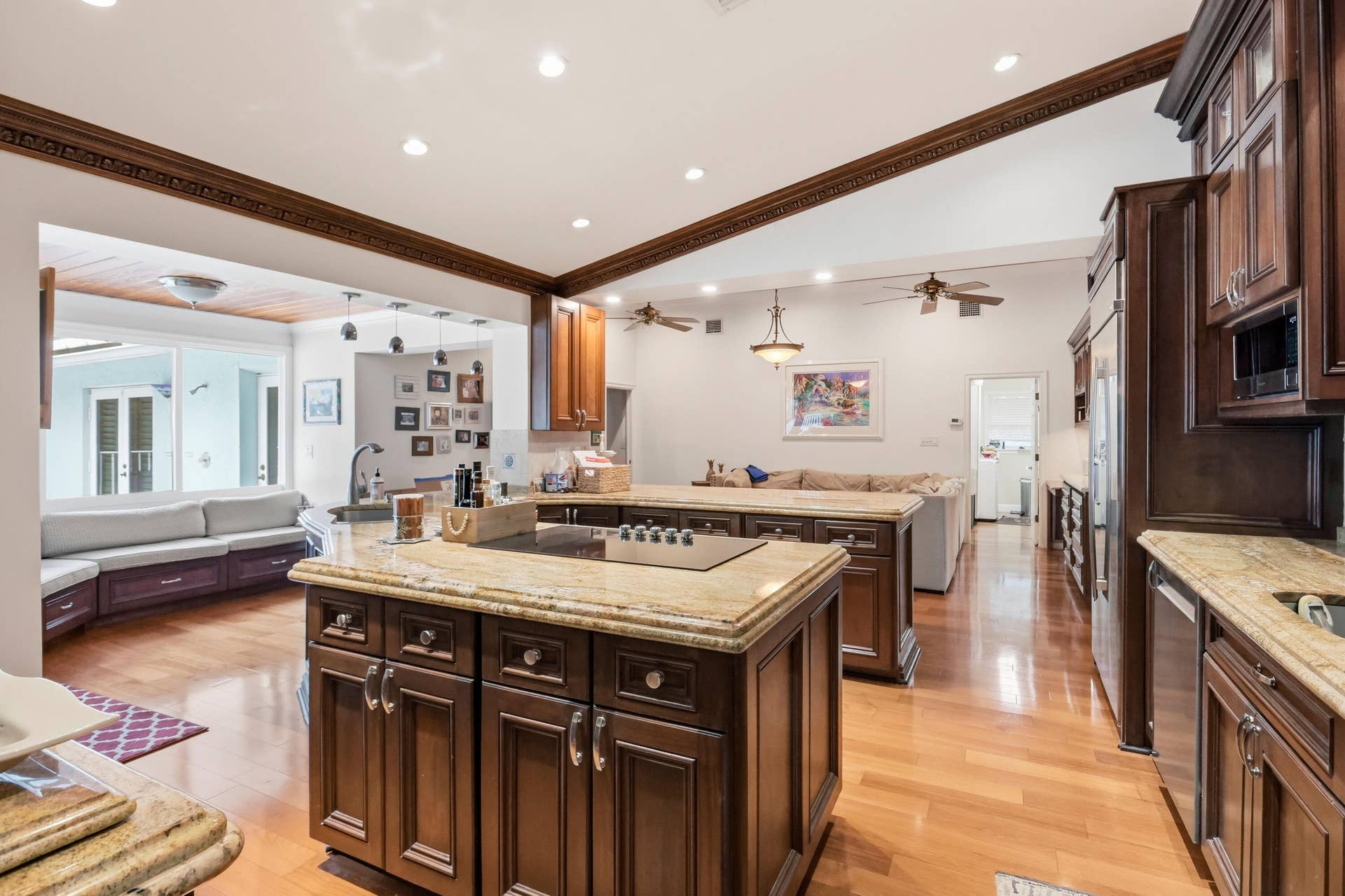 2919 Banyan Blvd Circle NW, Boca Raton, FL 33431 Kitchen featuring dark wood cabinetry, expansive stone countertops, an integrated cooktop on the center island, recessed ceiling lighting, and wood-finish flooring