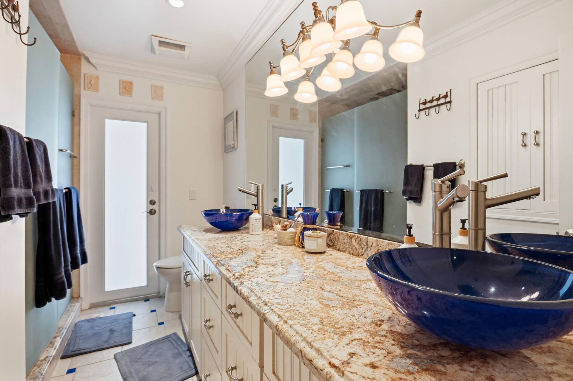 2919 Banyan Blvd Circle NW, Boca Raton, FL 33431 Double vanity featuring stone countertops, integrated blue vessel sinks, brushed nickel fixtures, custom cabinetry, and a full-width mirror