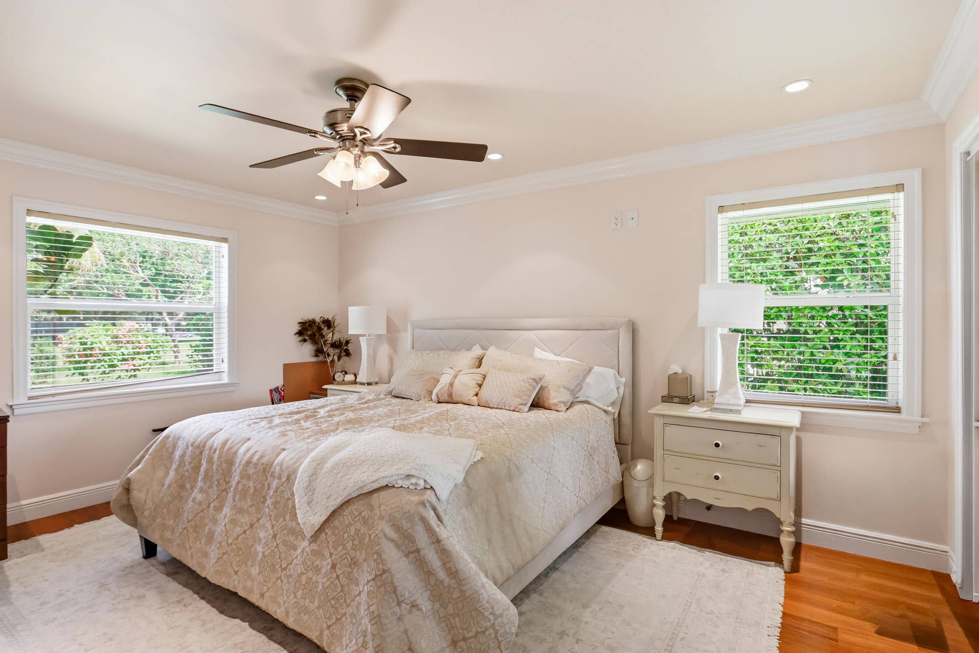 2919 Banyan Blvd Circle NW, Boca Raton, FL 33431 Neutral-toned room featuring crown molding, wood-finish flooring, dual windows with blinds, and a multi-blade ceiling fan with integrated light fixture