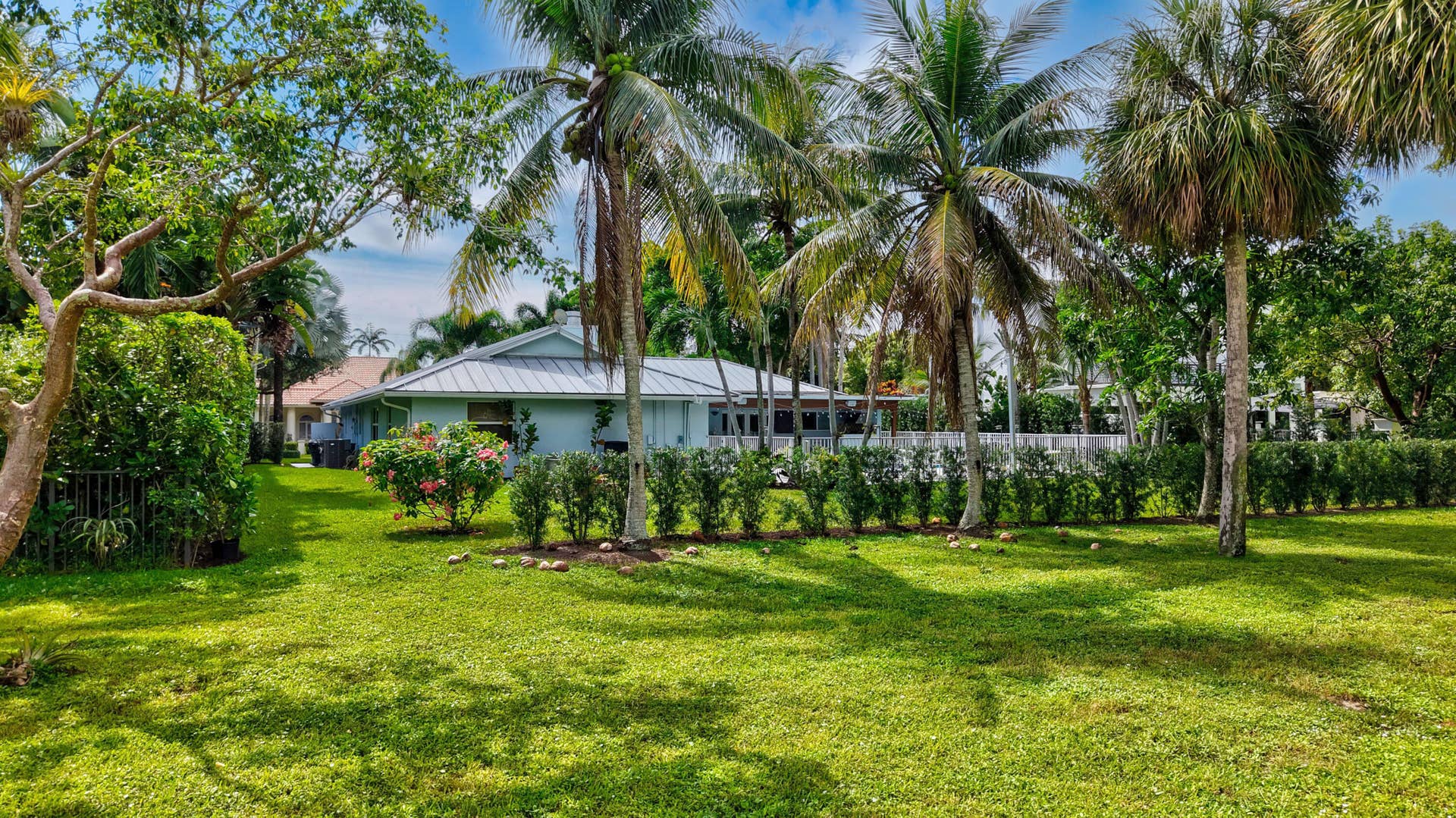 2919 Banyan Blvd Circle NW, Boca Raton, FL 33431 Expansive lawn with mature palm trees, perimeter shrubbery, and metal roofing