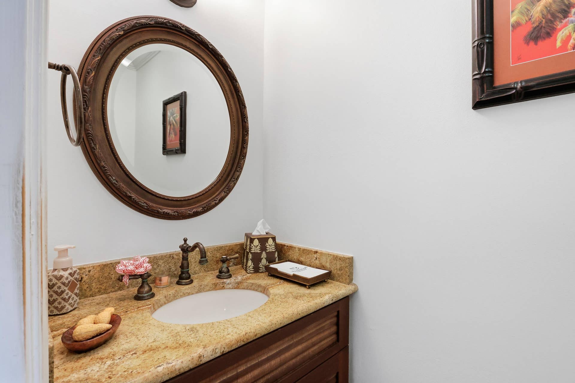 2919 Banyan Blvd Circle NW, Boca Raton, FL 33431 Vanity featuring a stone countertop with an integrated oval sink, dark wood-finish cabinetry, ornate round wall mirror, and dual-handle bronze faucet