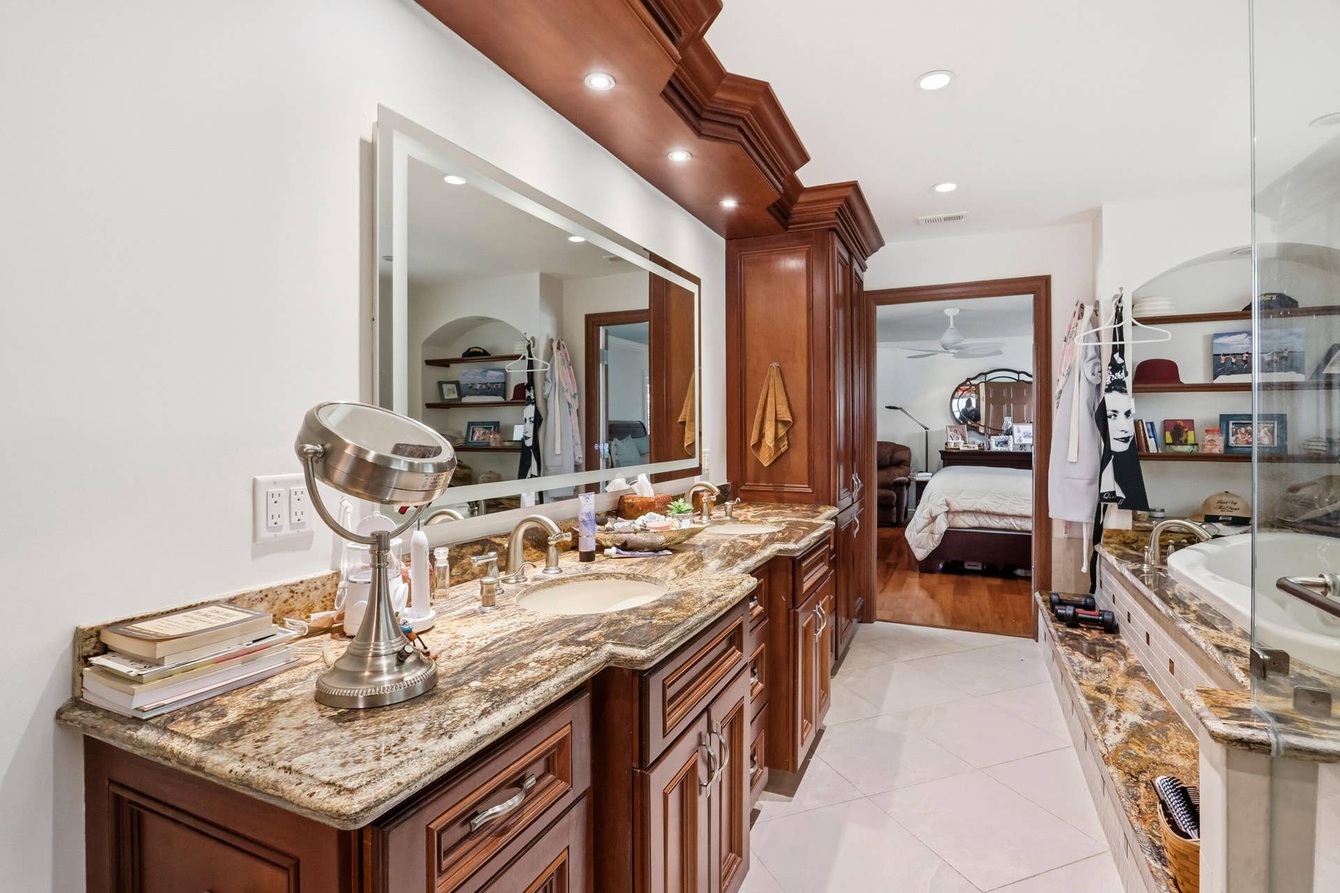 2919 Banyan Blvd Circle NW, Boca Raton, FL 33431 Double vanity featuring custom wood cabinetry, natural stone countertops, dual integrated sinks, and a large backlit mirror with integrated recessed lighting