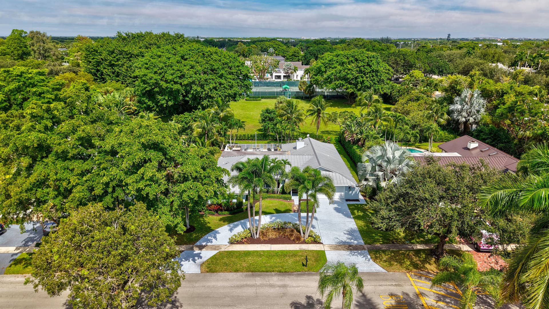 2919 Banyan Blvd Circle NW, Boca Raton, FL 33431 Aerial view featuring a metal roofing system, paved driveway, landscaped perimeter, and mature canopy trees