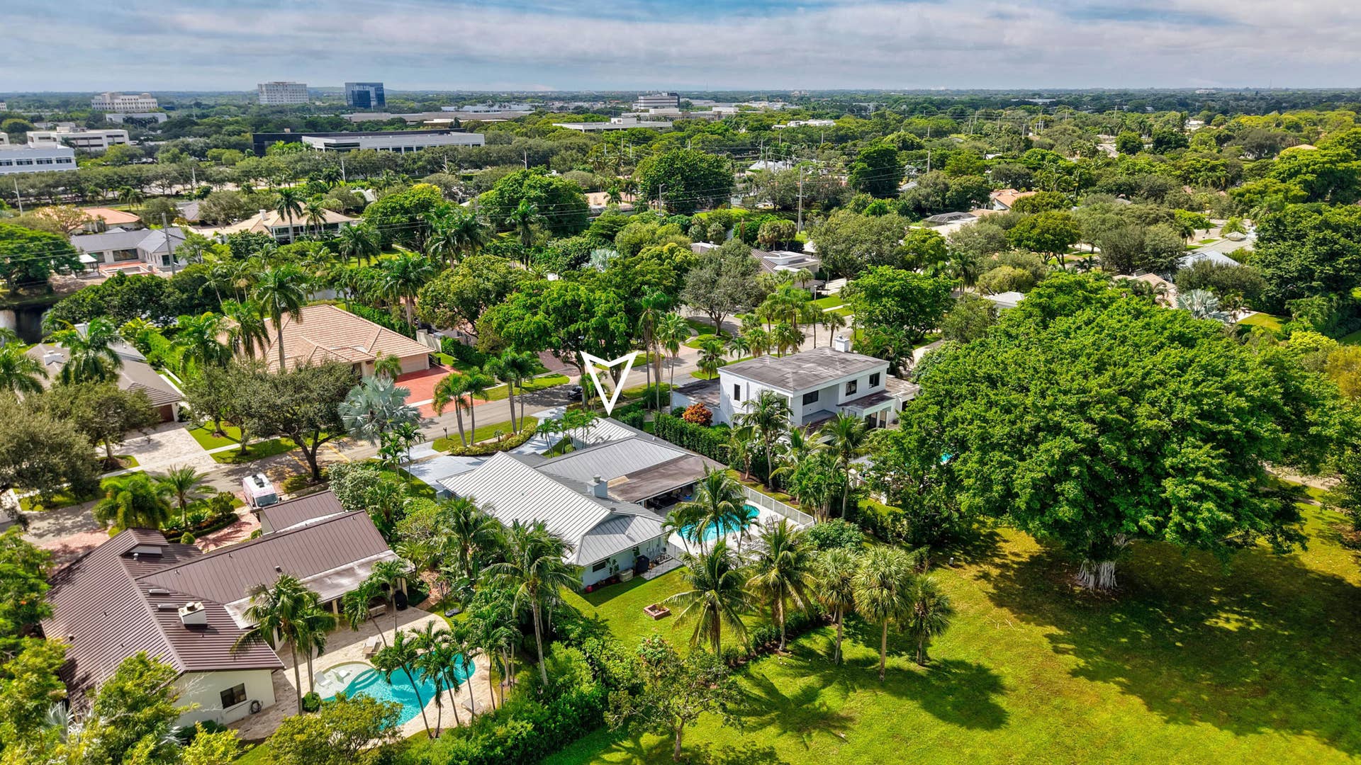 2919 Banyan Blvd Circle NW, Boca Raton, FL 33431 Aerial perspective featuring a single-story residence with a metal roof, an in-ground swimming pool, a concrete patio, and mature landscaping within a suburban setting