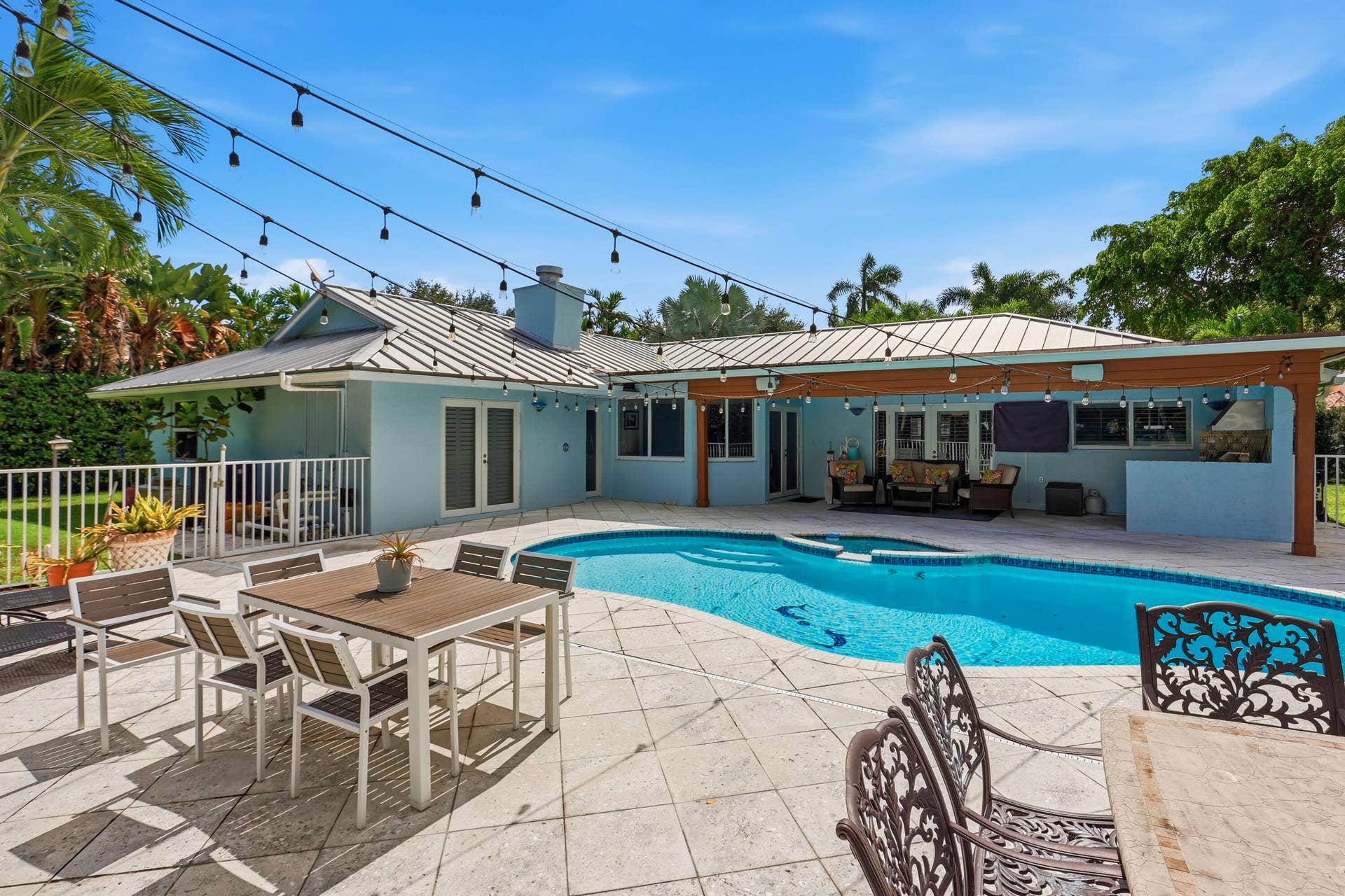 2919 Banyan Blvd Circle NW, Boca Raton, FL 33431 Backyard featuring a custom-shaped swimming pool, expansive paved patio, covered outdoor living area, and built-in masonry grill