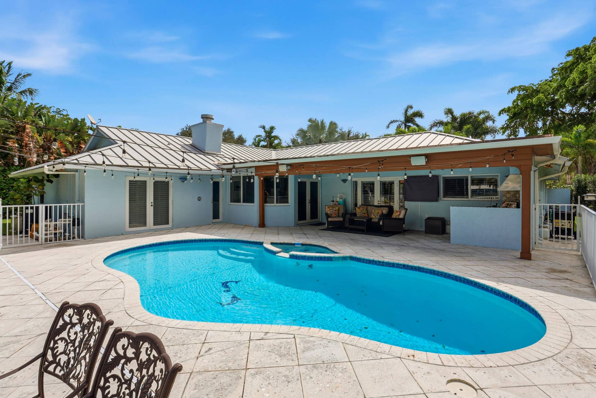 2919 Banyan Blvd Circle NW, Boca Raton, FL 33431 Outdoor living area featuring a covered lanai, built-in masonry grill, custom-shaped swimming pool with integrated spa, and expansive stone-paver decking
