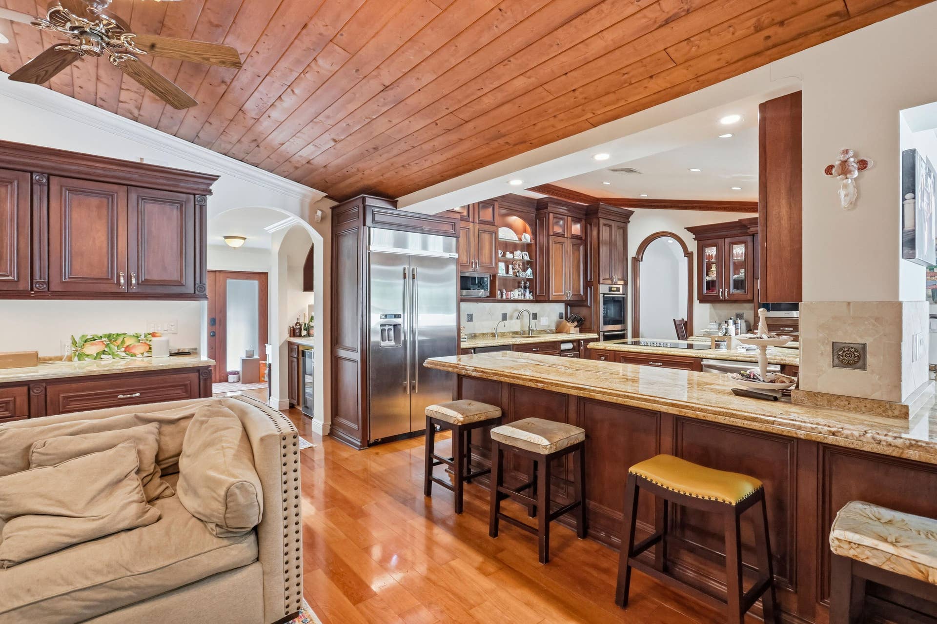 2919 Banyan Blvd Circle NW, Boca Raton, FL 33431 Kitchen featuring wood-plank ceiling, stained wood cabinetry, natural stone countertops, a multi-level breakfast bar, and wood-finish flooring