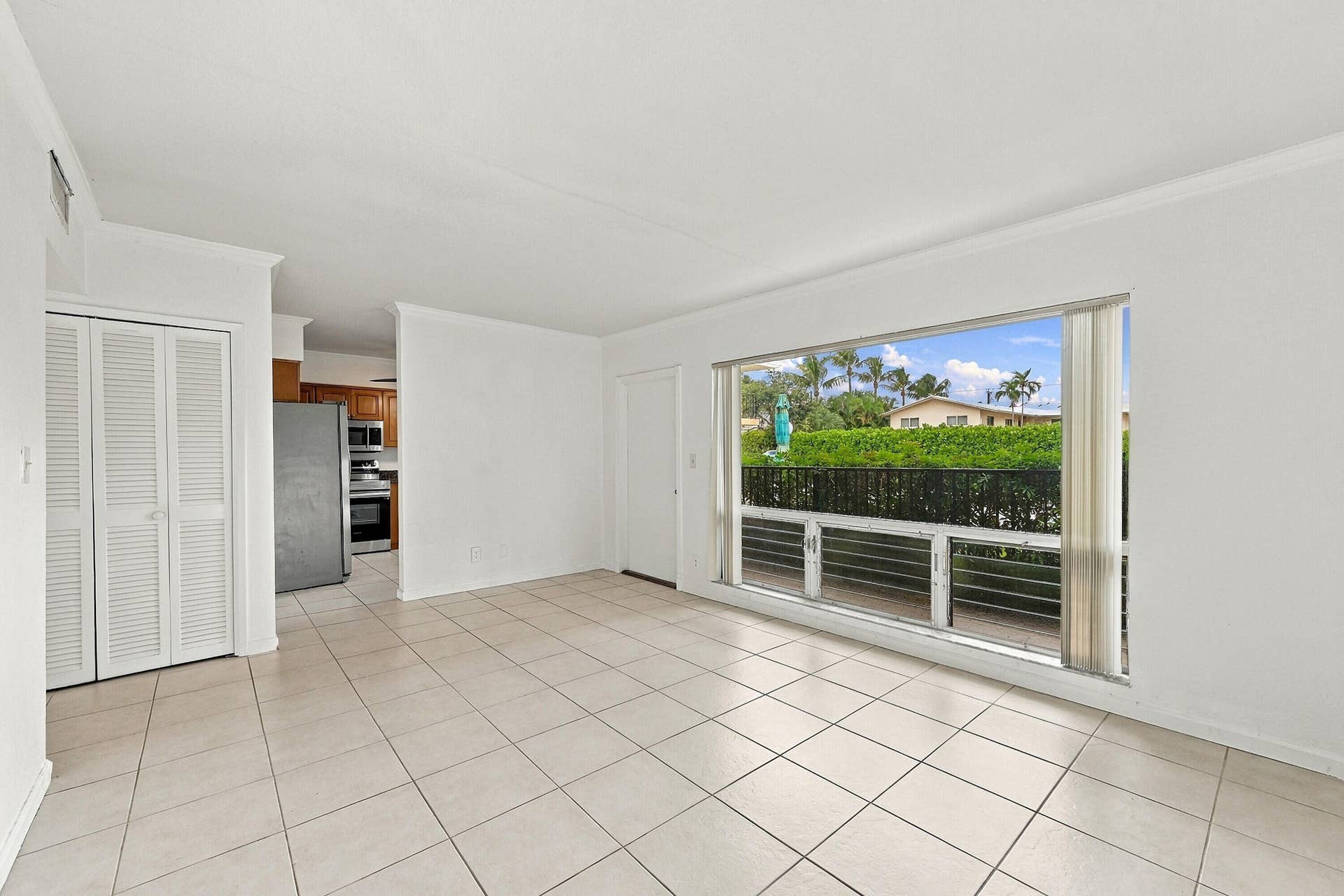 Living area featuring large-format ceramic tile flooring, floor-to-ceiling windows, and built-in louvered closet doors