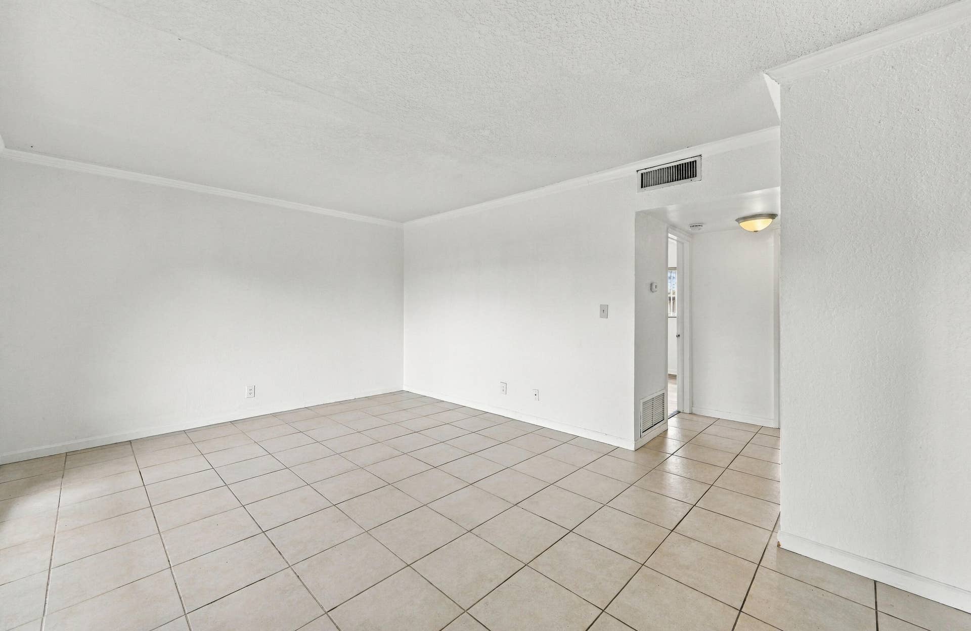 Interior space featuring neutral wall tones, large-format ceramic tile flooring, and a flush-mount overhead light fixture