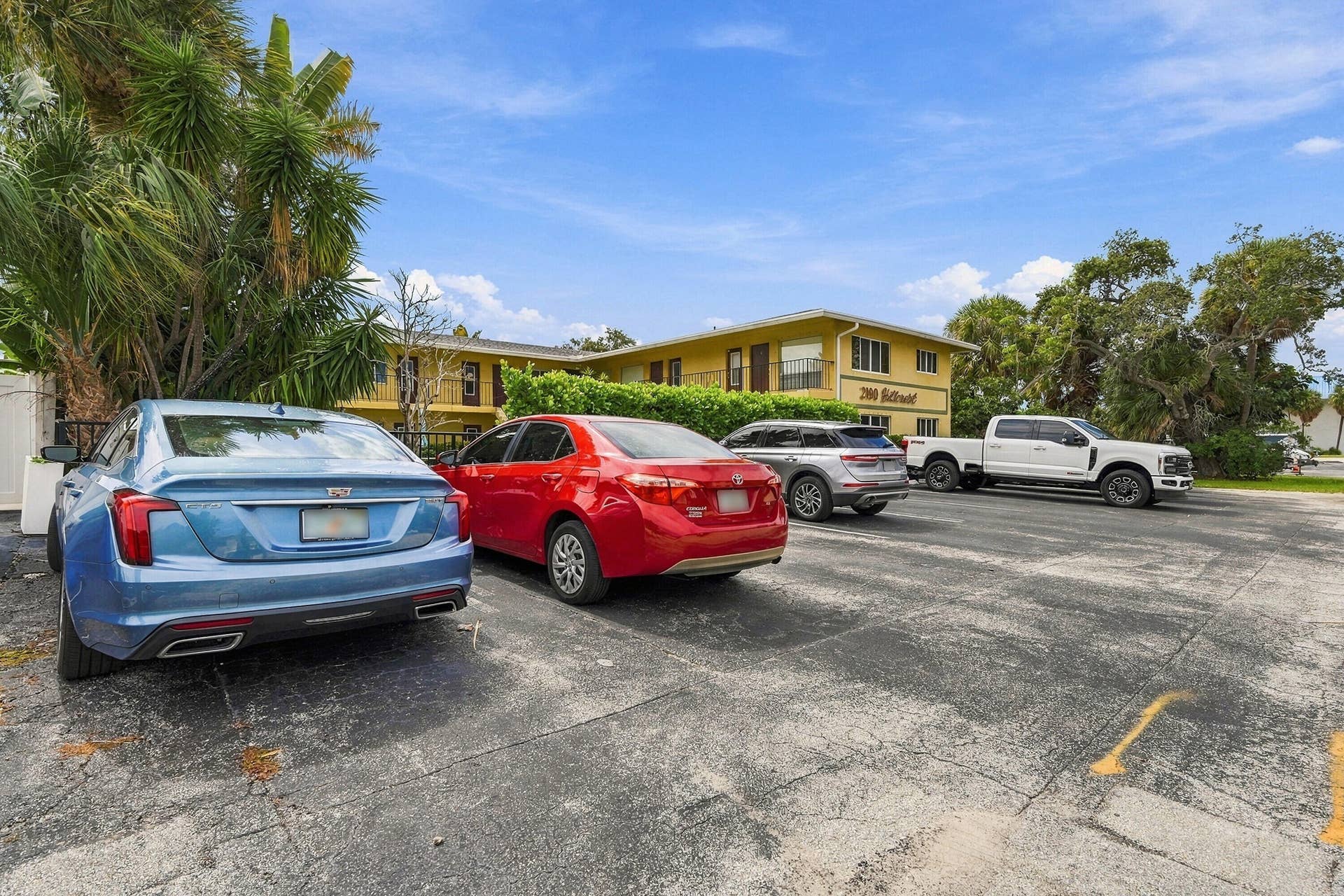 Multi-level exterior featuring a paved parking area and mature landscaping