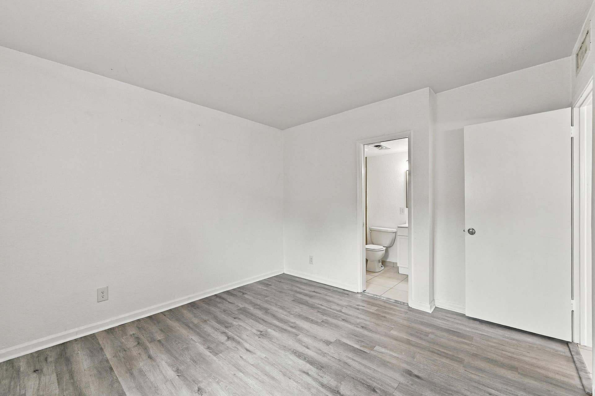 Interior space featuring wood-finish flooring, white walls, and a solid-core interior door