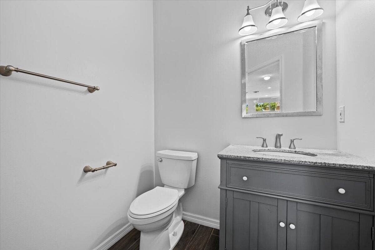 Main-level powder room featuring a vanity with storage and decorative mirror.