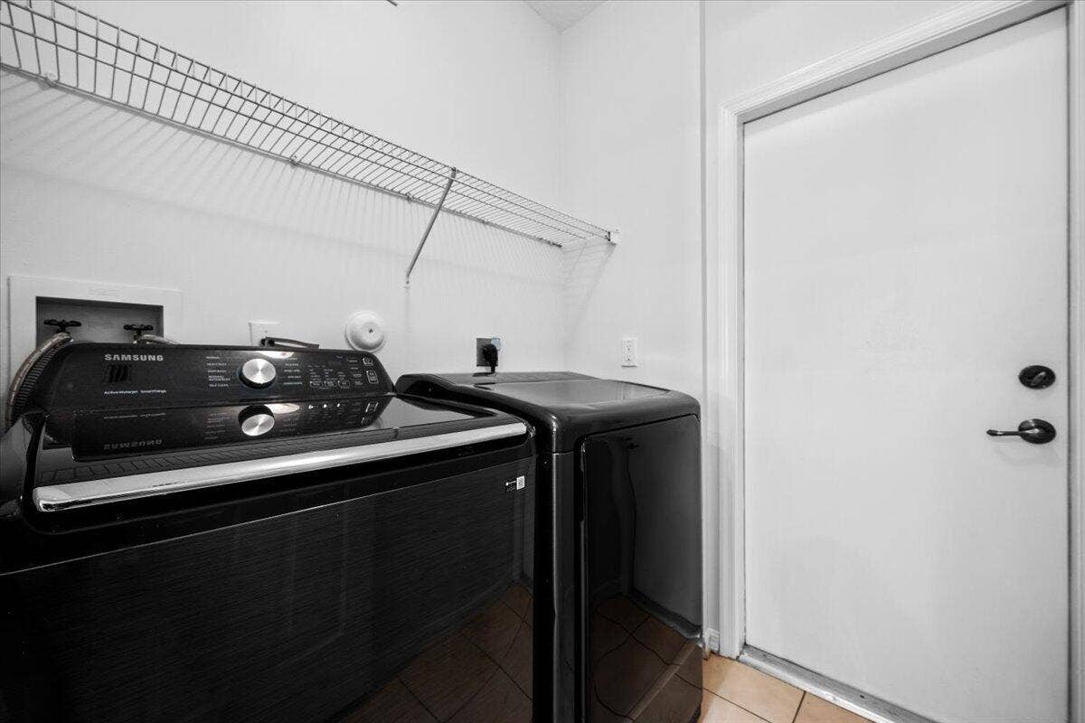 Convenient laundry area with washer, dryer, and overhead storage shelving.