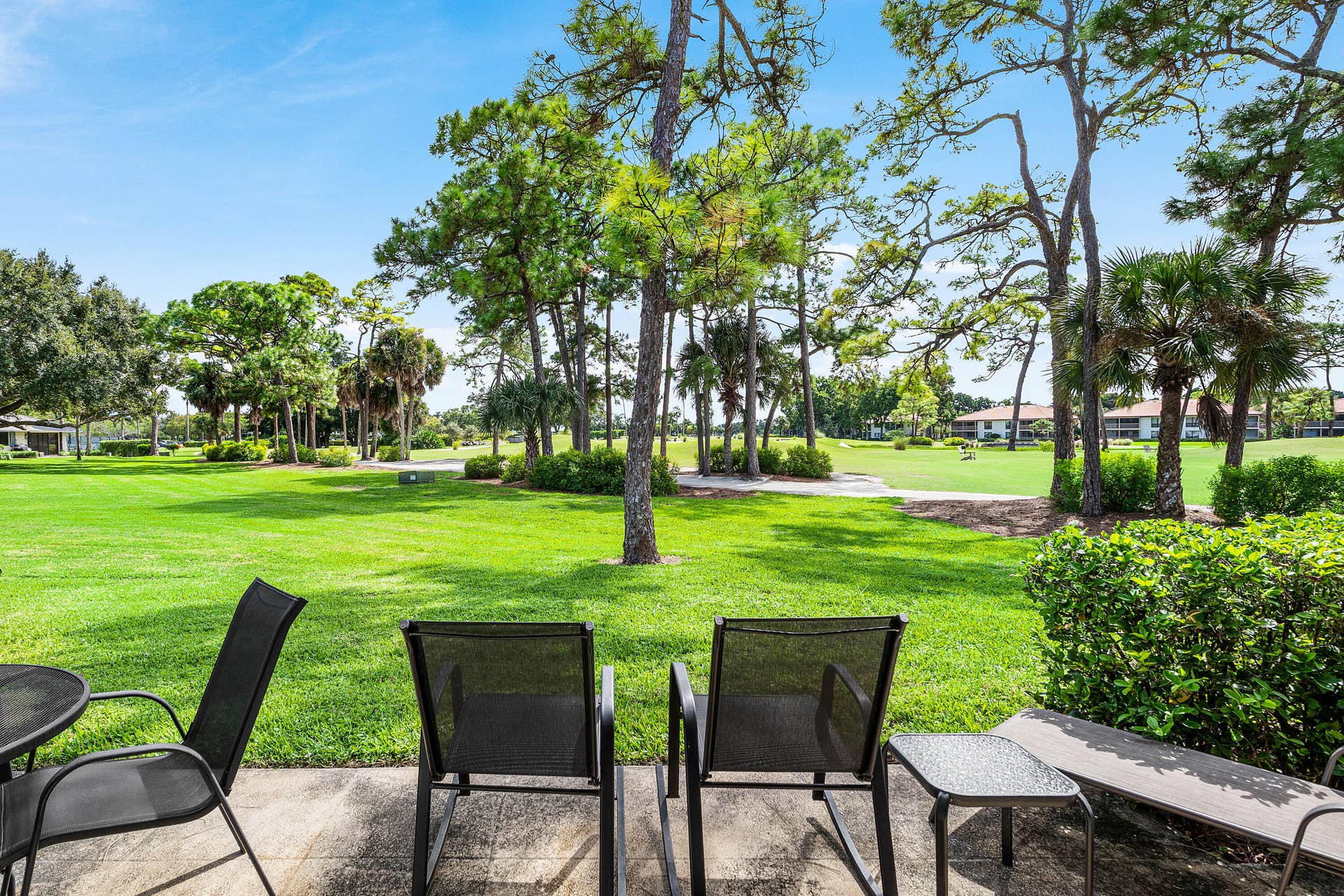 526 Club Drive, Palm Beach Gardens, FL 33418 Concrete patio overlooking a sprawling lawn with mature trees and native landscaping