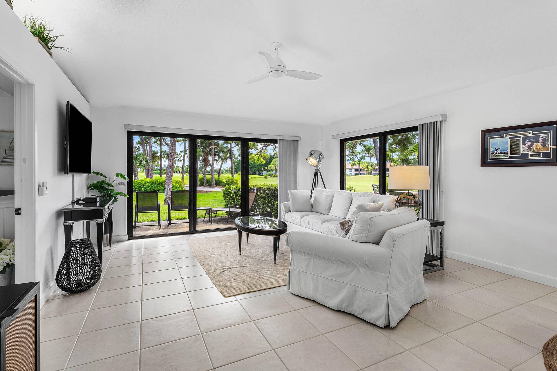 526 Club Drive, Palm Beach Gardens, FL 33418 Living area featuring large-format neutral tile flooring, expansive sliding glass doors, and a ceiling-mounted fan