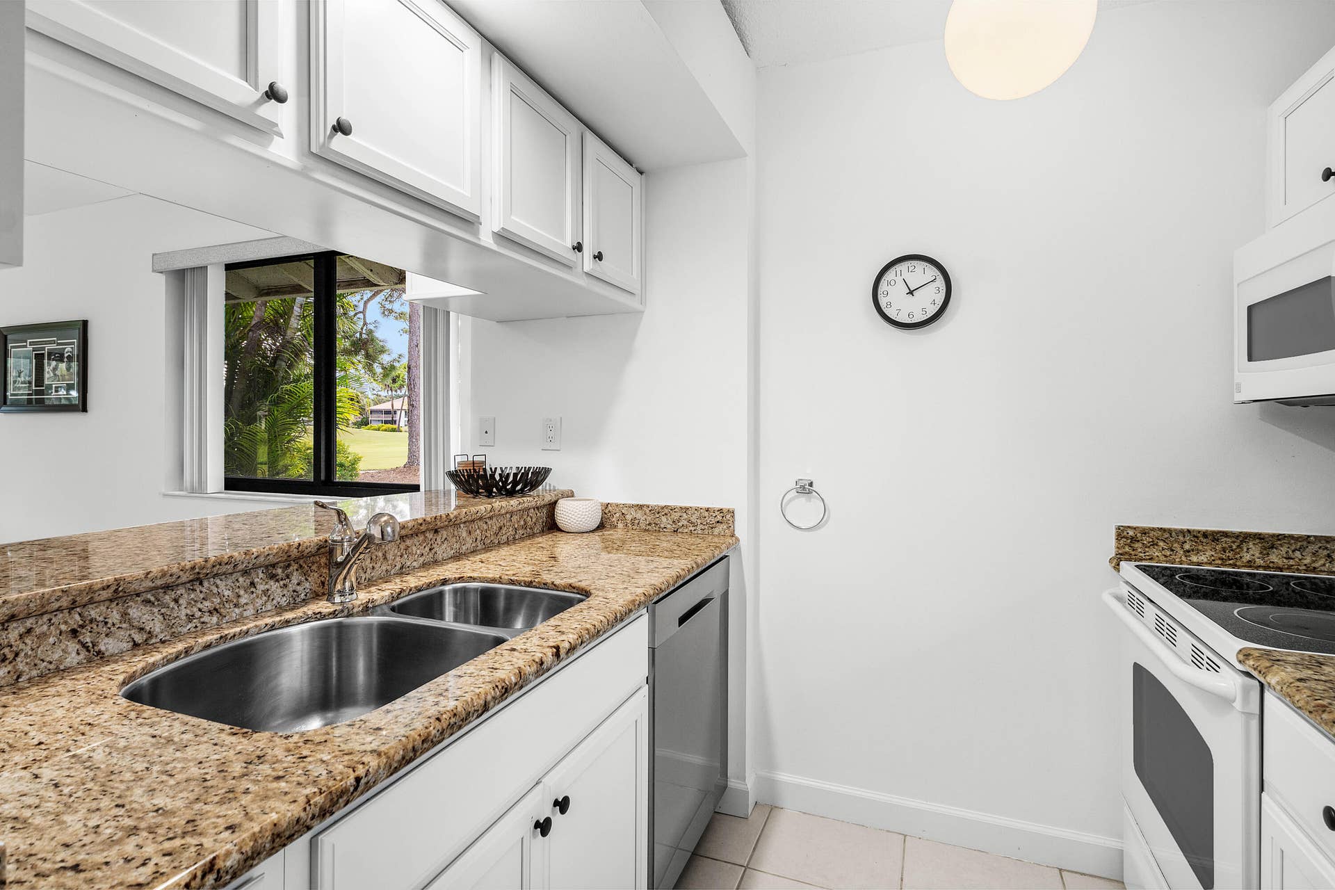 526 Club Drive, Palm Beach Gardens, FL 33418 Kitchen featuring white shaker-style cabinetry, stone countertops, dual-basin stainless steel sink with a high-arch faucet, integrated stainless steel dishwasher, and built-in white electric range with overhead microwave