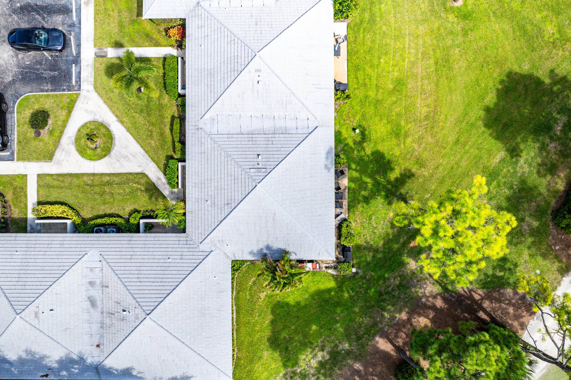 526 Club Drive, Palm Beach Gardens, FL 33418 Aerial perspective of property featuring a hip roof, concrete paved walkways, expansive manicured lawn, and mature trees