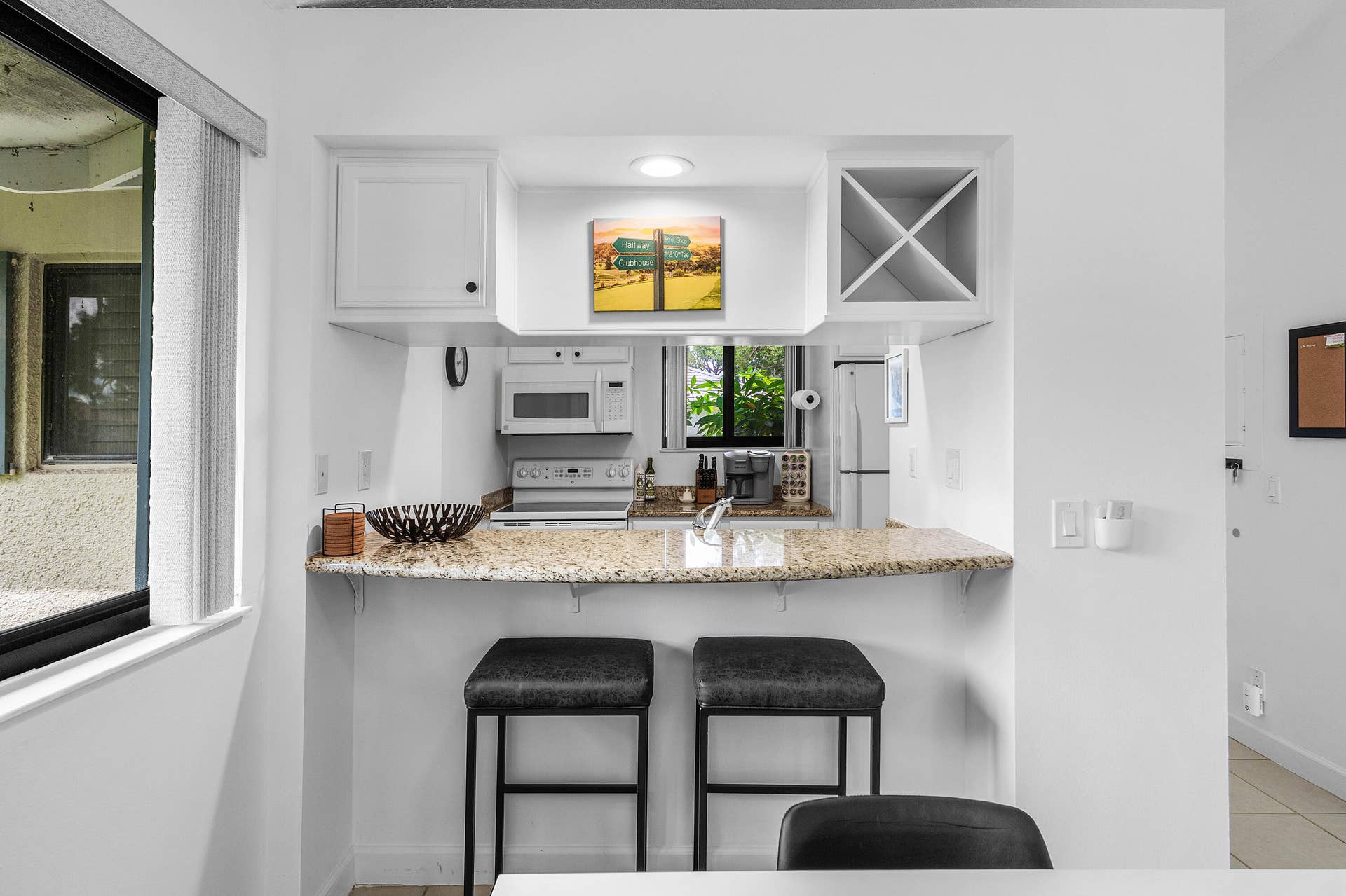 526 Club Drive, Palm Beach Gardens, FL 33418 Kitchen featuring a stone countertop breakfast bar, custom cabinetry including built-in wine storage, recessed lighting, and a white built-in microwave
