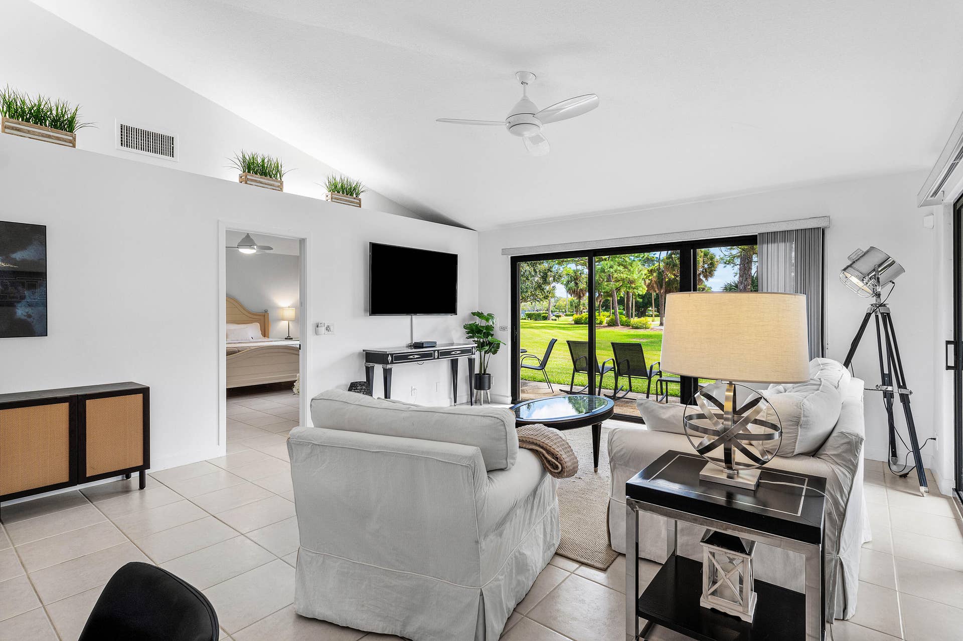 526 Club Drive, Palm Beach Gardens, FL 33418 Vaulted ceiling featuring a central cooling fan and large-format tile flooring, highlighted by sliding glass doors opening to outdoor green space