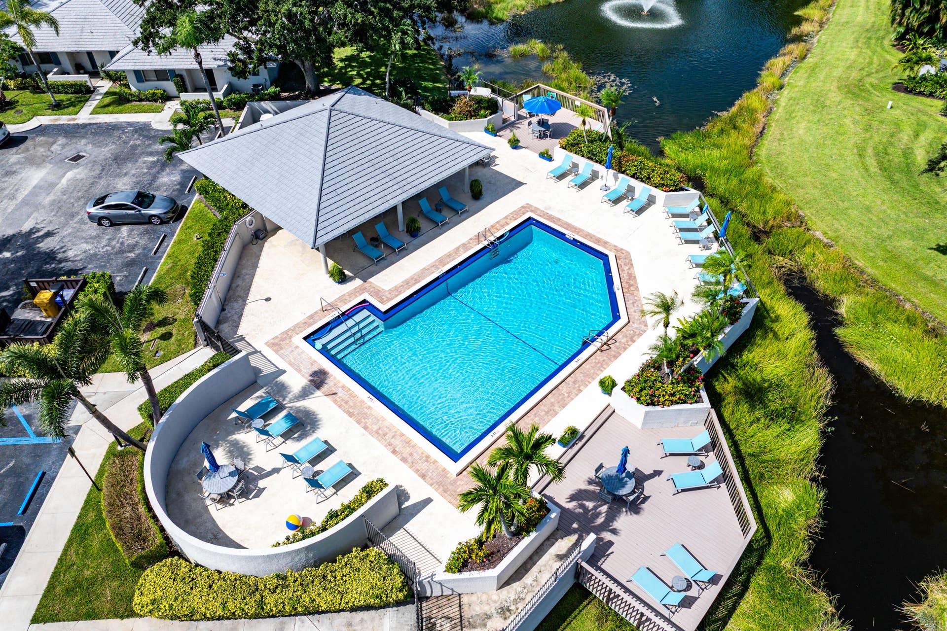 526 Club Drive, Palm Beach Gardens, FL 33418 Community swimming pool featuring a geometric basin, surrounding paved deck, covered pavilion, and integrated landscaping