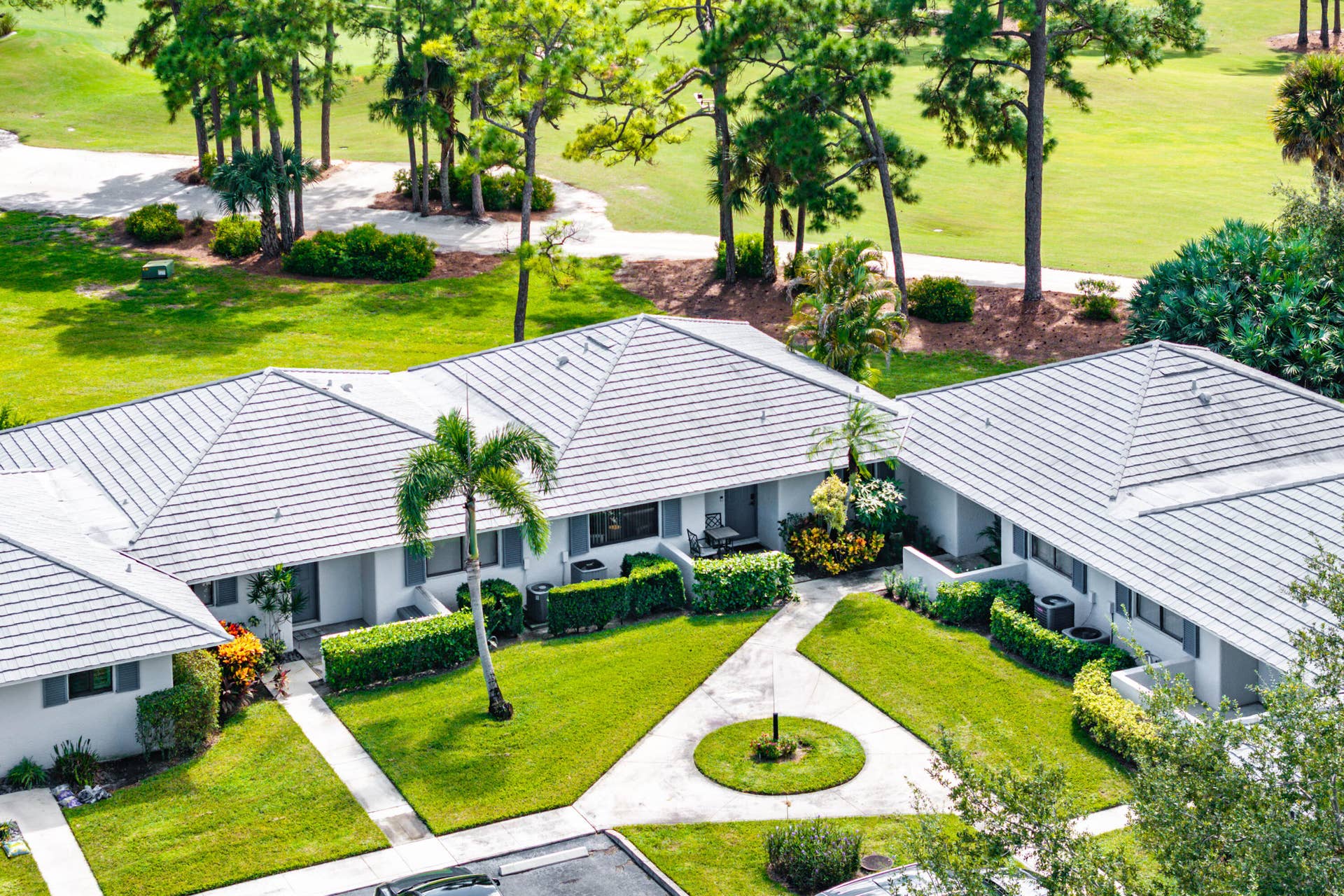 526 Club Drive, Palm Beach Gardens, FL 33418 Aerial view of a residential complex featuring light-colored roof tiles, stucco siding, manicured green space, concrete walkways, and mature landscaping