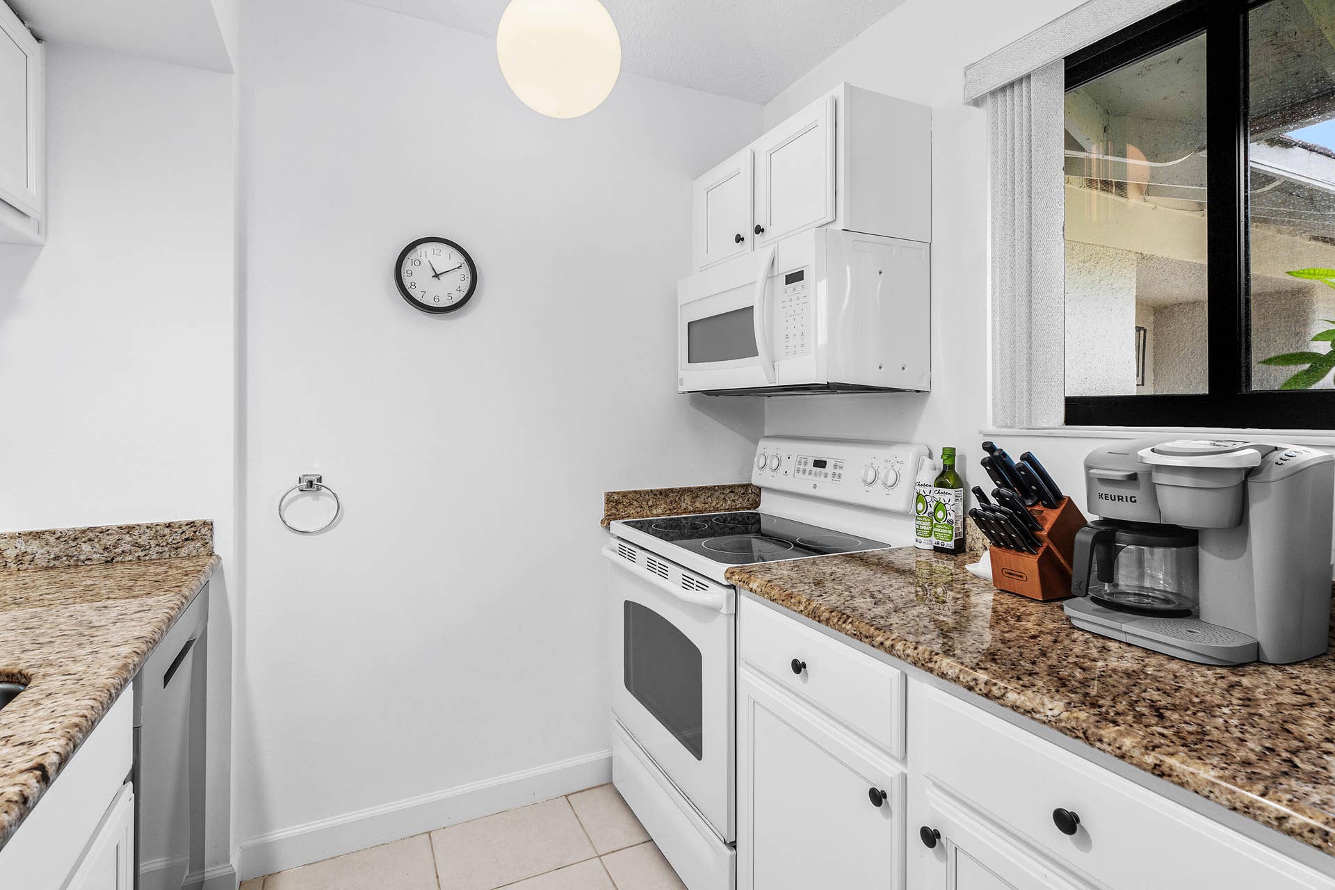 526 Club Drive, Palm Beach Gardens, FL 33418 Kitchen featuring white cabinetry, stone-finish countertops, built-in microwave, integrated range, and ceramic tile flooring