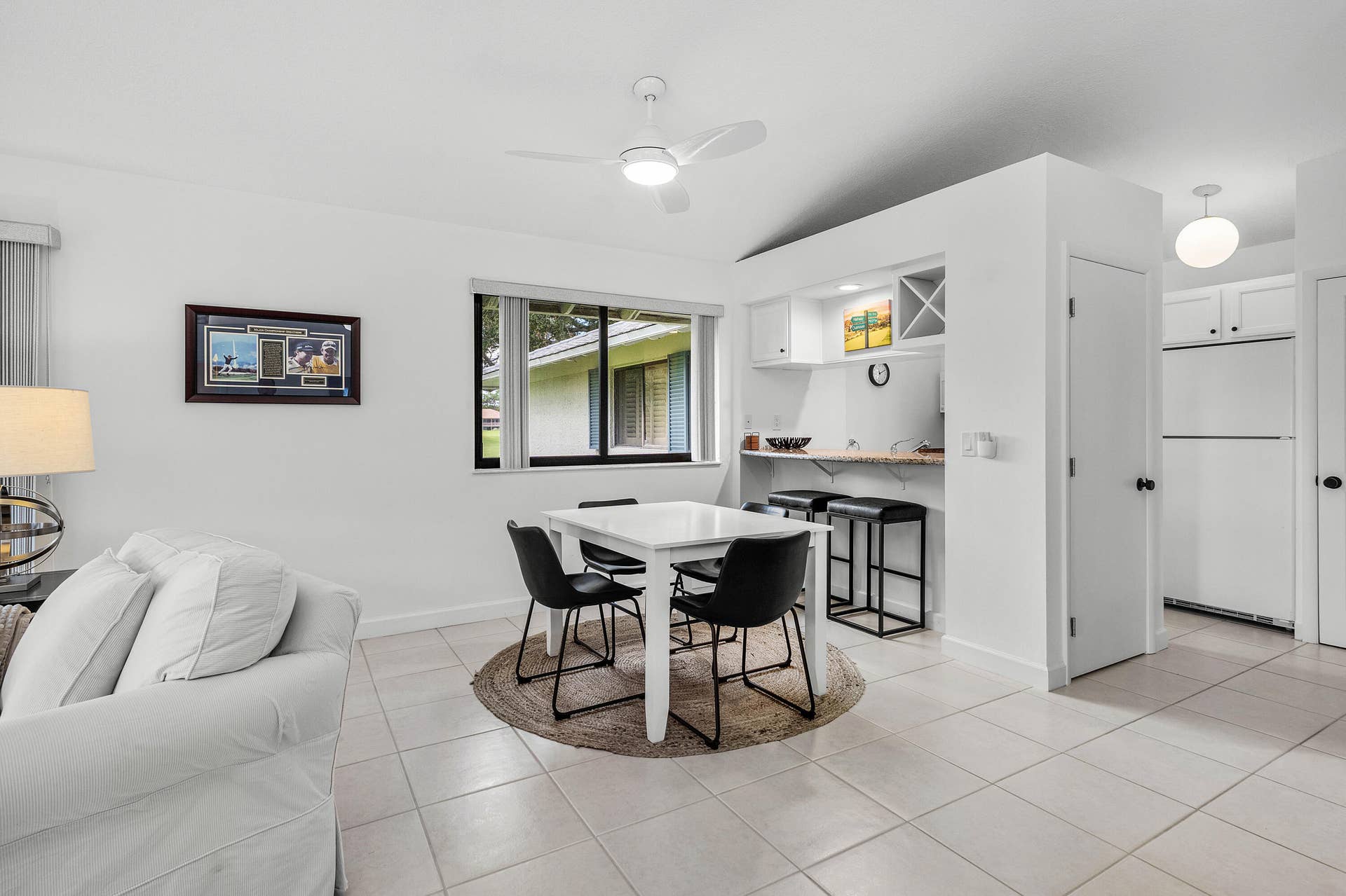 526 Club Drive, Palm Beach Gardens, FL 33418 Tile flooring, integrated bar area with built-in wine rack, white cabinetry, ceiling fan with integrated lighting, and neutral wall color palette