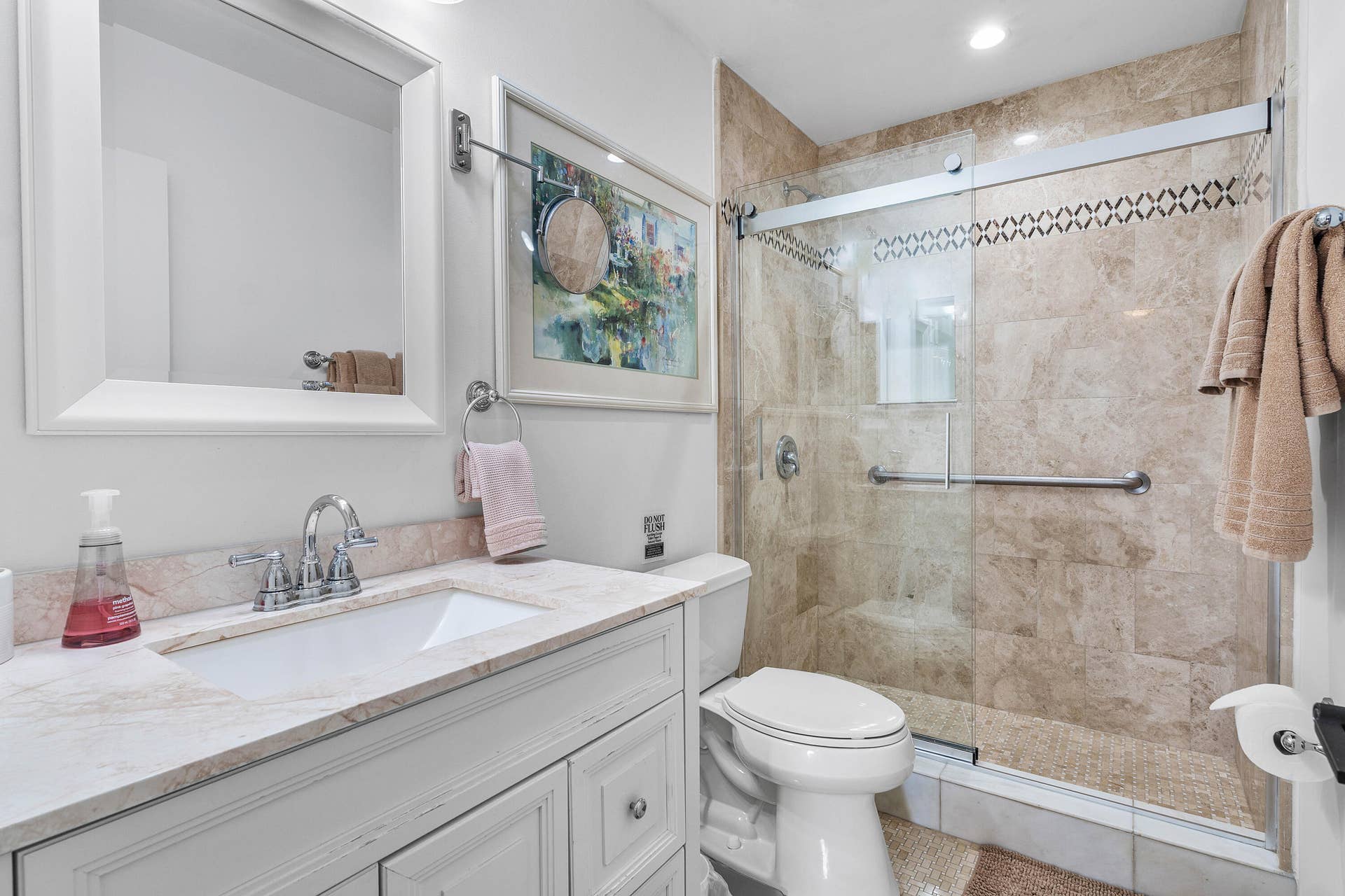526 Club Drive, Palm Beach Gardens, FL 33418 Bathroom featuring a white vanity with stone countertop, undermount sink, framed mirror, and a walk-in shower with stone tile surround and sliding glass doors