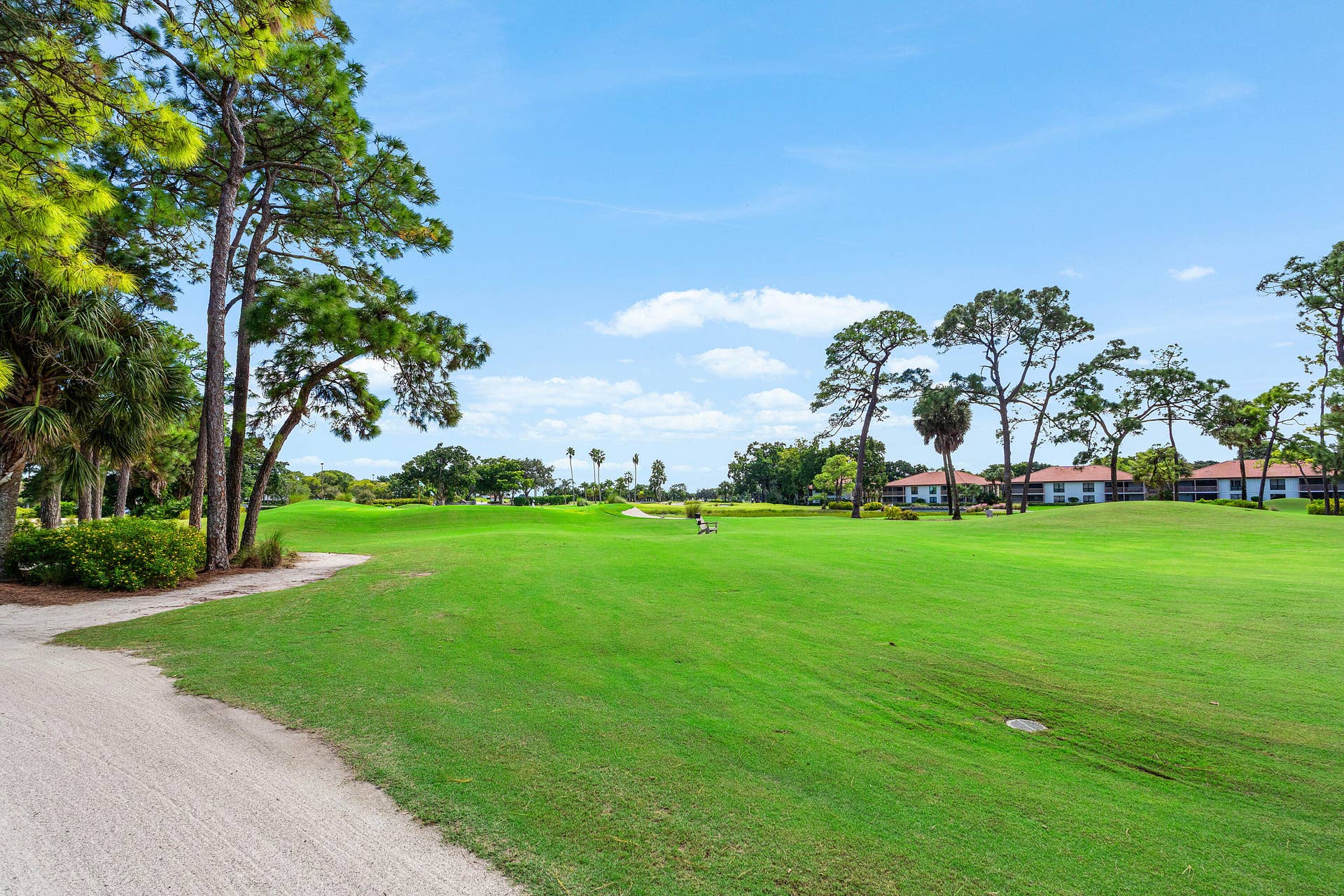 526 Club Drive, Palm Beach Gardens, FL 33418 Expansive green space featuring mature pine trees, manicured turf, and a crushed stone path