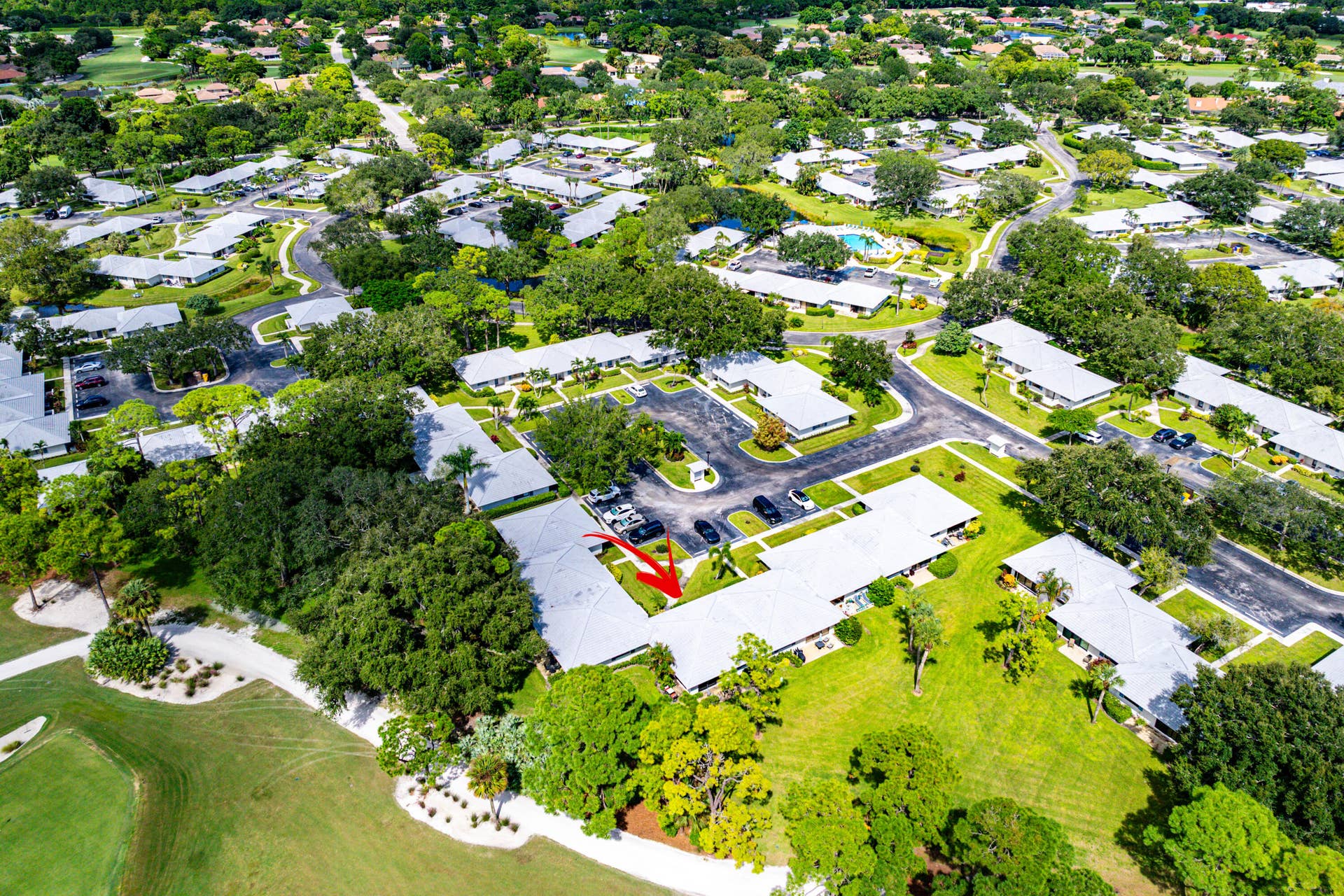 526 Club Drive, Palm Beach Gardens, FL 33418 Aerial perspective of residential property featuring a light-colored roof, surrounded by mature trees, expansive green lawns, and proximity to golf course grounds