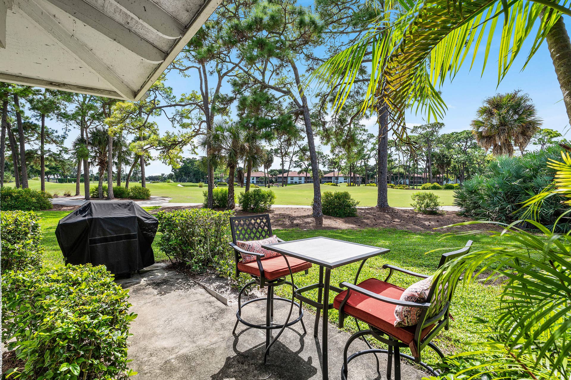 526 Club Drive, Palm Beach Gardens, FL 33418 Covered concrete patio featuring landscape hedging and mature trees