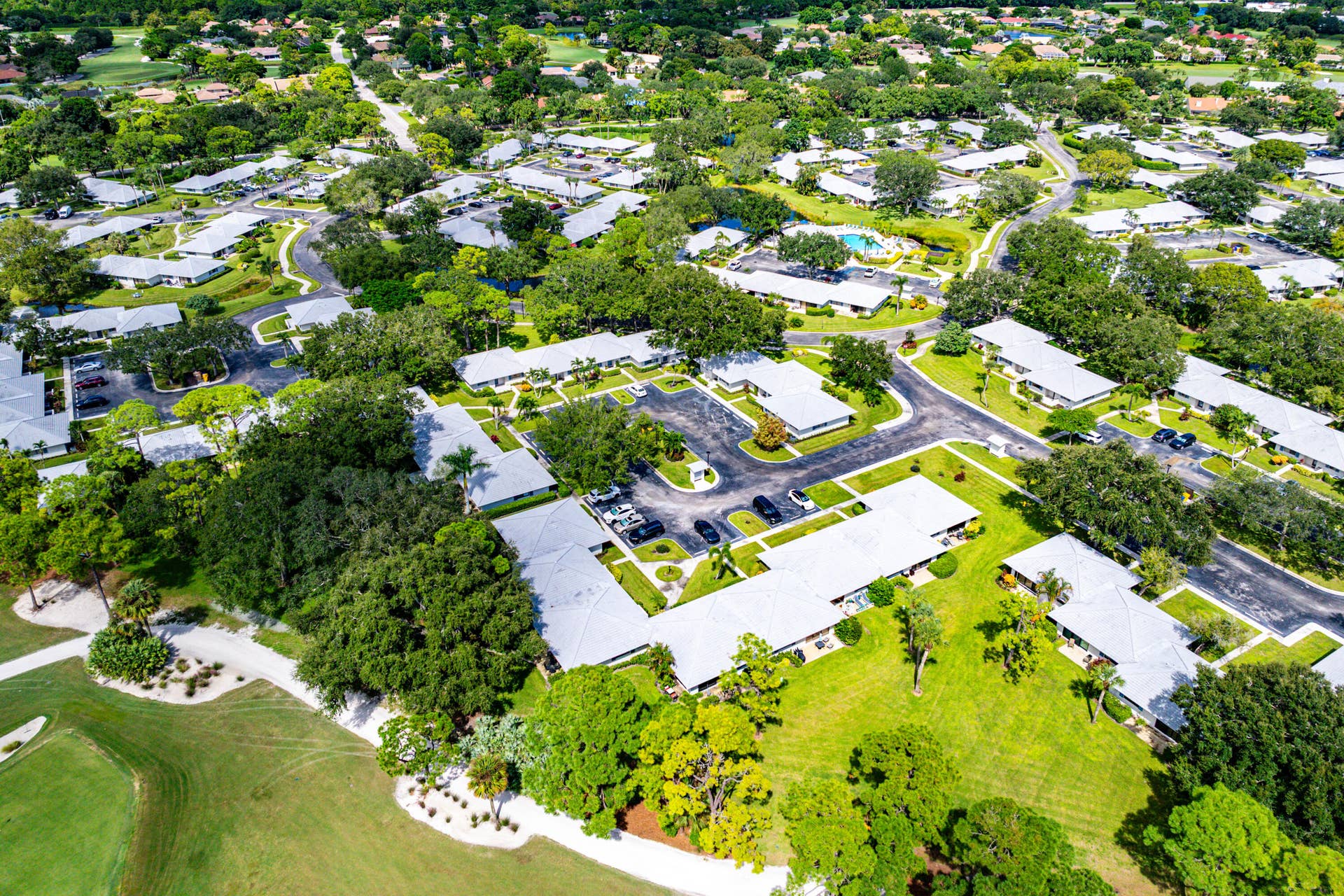 526 Club Drive, Palm Beach Gardens, FL 33418 Aerial perspective featuring residential buildings with light-toned roof shingles, extensive mature tree canopy, integrated paved roadways, and landscaped green space