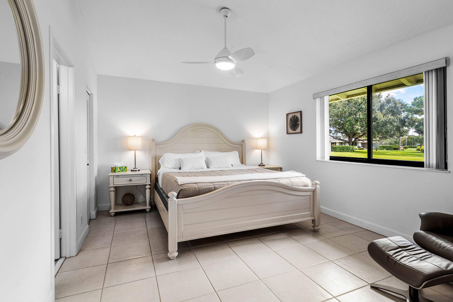 526 Club Drive, Palm Beach Gardens, FL 33418 Neutral-toned ceramic tile flooring, ceiling fan with integrated lighting, and oversized window featuring a landscape backdrop