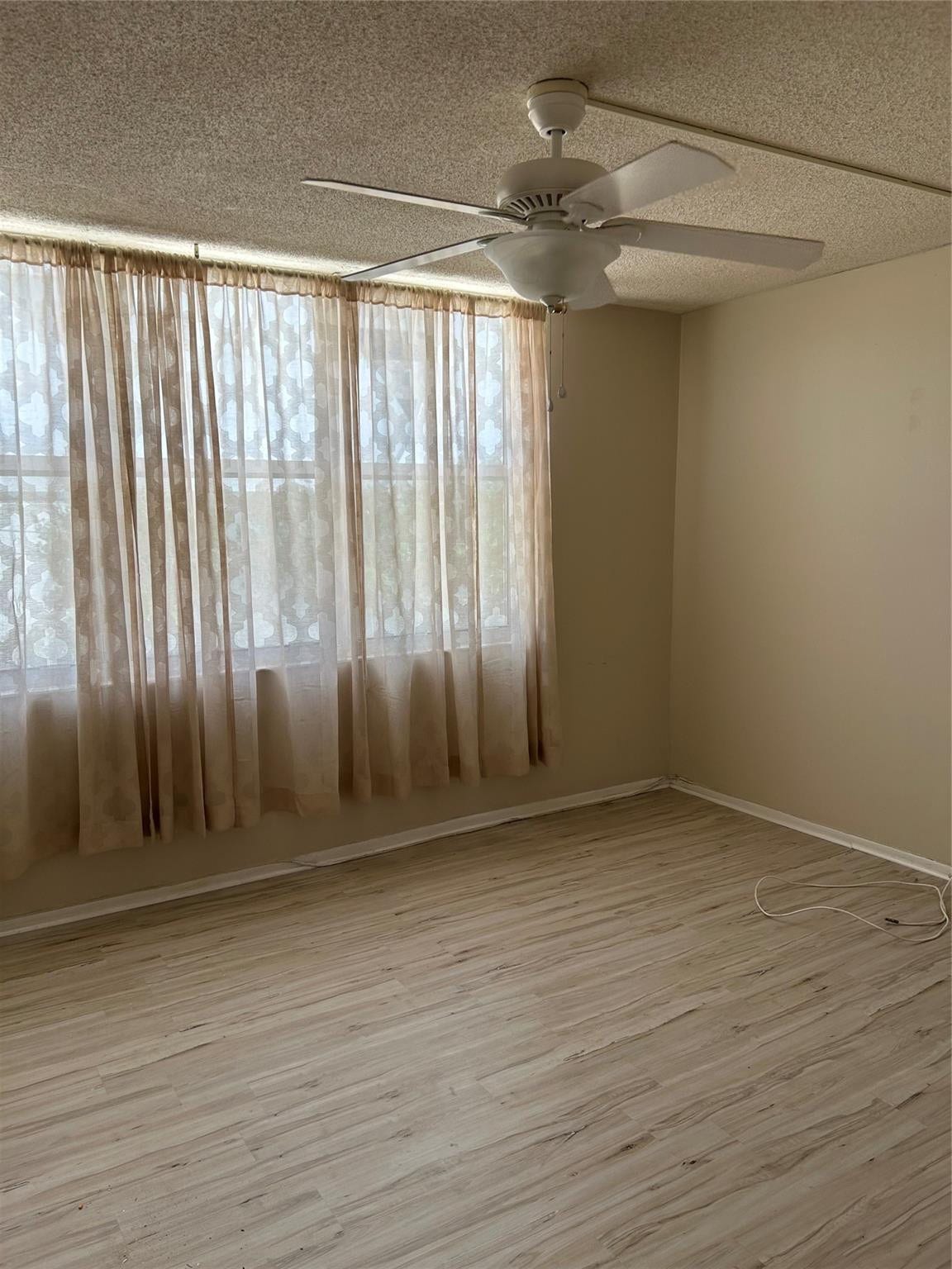 305 N POMPANO BEACH Boulevard, #206, Pompano Beach, Pompano Beach, FL 33062 Room featuring wood-finish flooring, a white ceiling fan with an integrated light fixture, and floor-to-ceiling windows