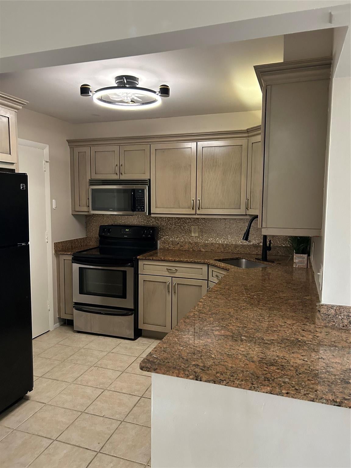 305 N POMPANO BEACH Boulevard, #206, Pompano Beach, Pompano Beach, FL 33062 Kitchen featuring light-toned cabinetry, stone-finish countertops, stainless steel appliances, ceramic tile flooring, and a modern circular flush-mount ceiling fixture