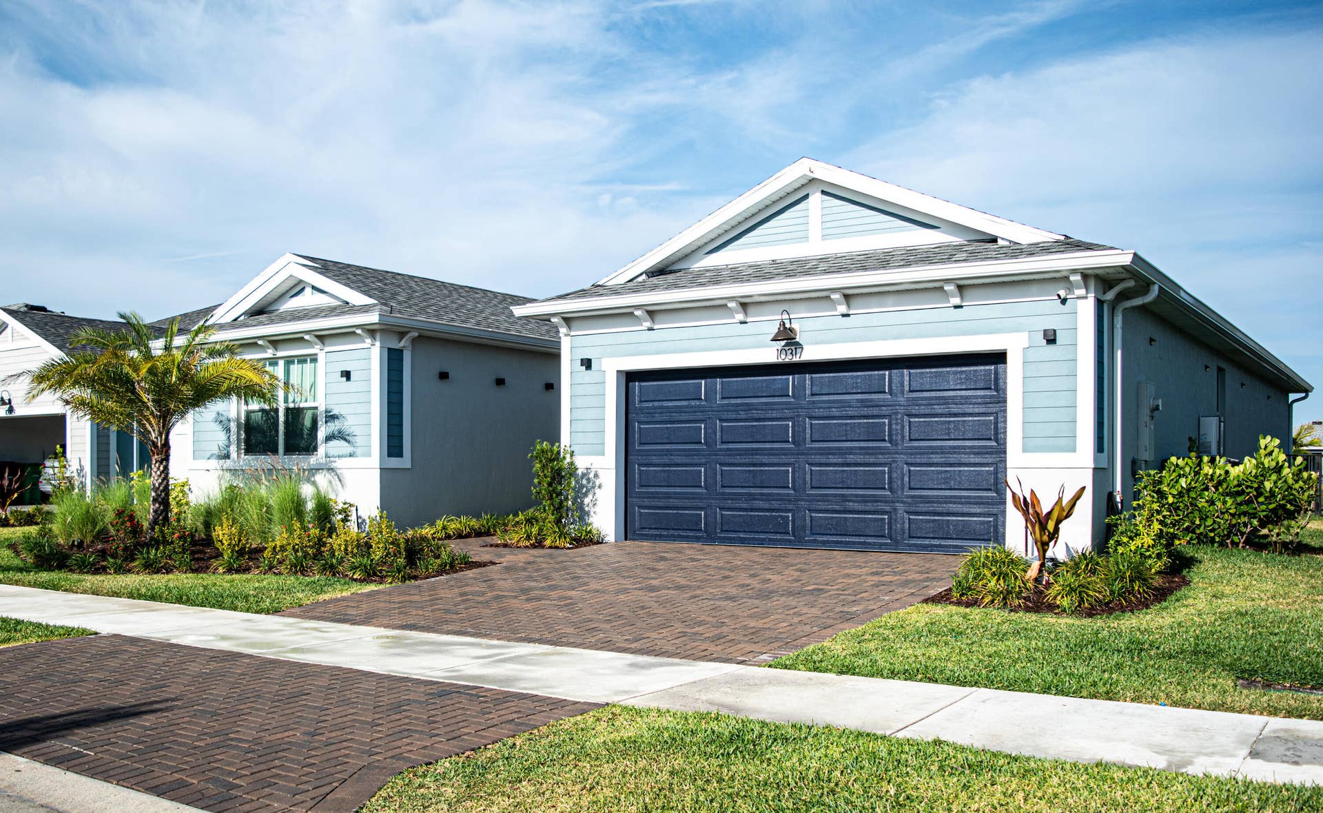 10317 SW Phineas Lane, Port St Lucie, FL 34987 Exterior featuring lap siding, asphalt shingle roof with gable accents, carriage-style garage door, and paver driveway