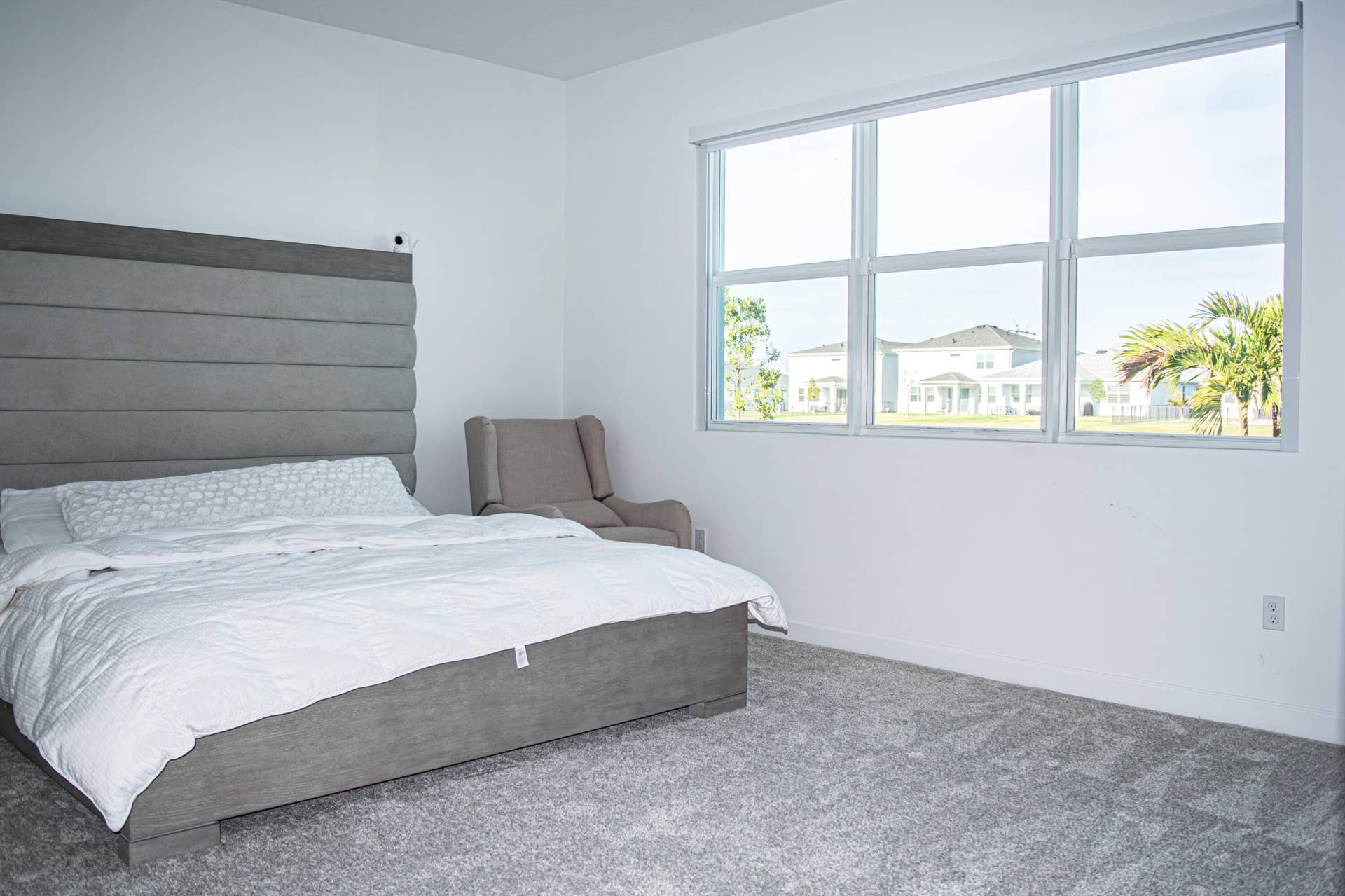 10317 SW Phineas Lane, Port St Lucie, FL 34987 Neutral-toned carpet flooring, oversized horizontal window with a retractable roller shade, and smooth white wall finishes