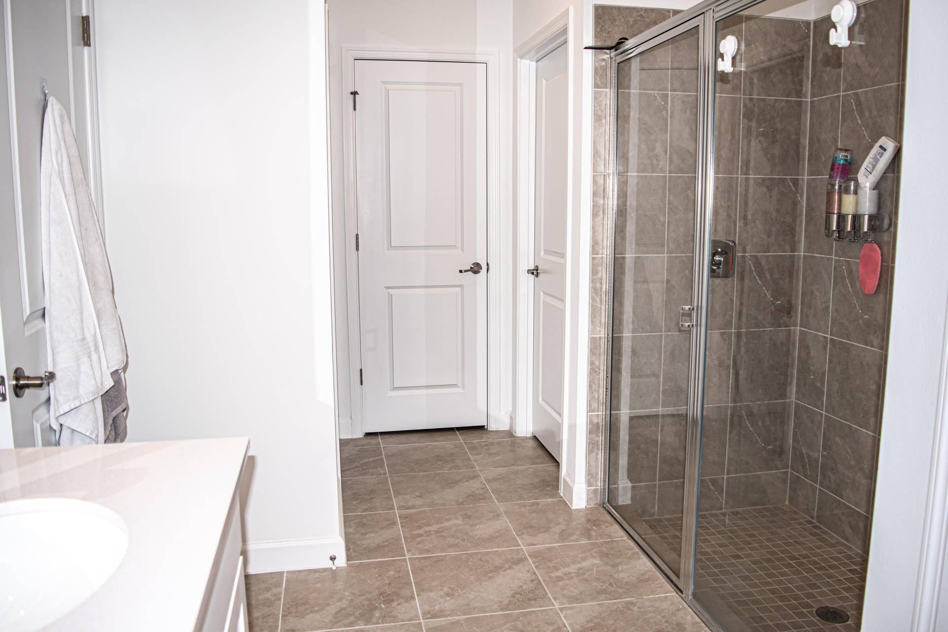 10317 SW Phineas Lane, Port St Lucie, FL 34987 Bathroom featuring a walk-in shower with glass enclosure, neutral tile flooring, tiled shower walls, and a vanity with a solid-surface countertop