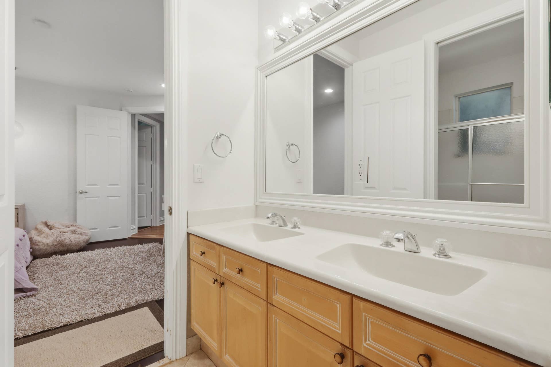 1580 VICTORIA ISLE Way, Weston, FL 33327 Double vanity featuring natural wood cabinetry, integrated white countertops with dual sinks, chrome fixtures, and a large framed wall mirror with integrated lighting