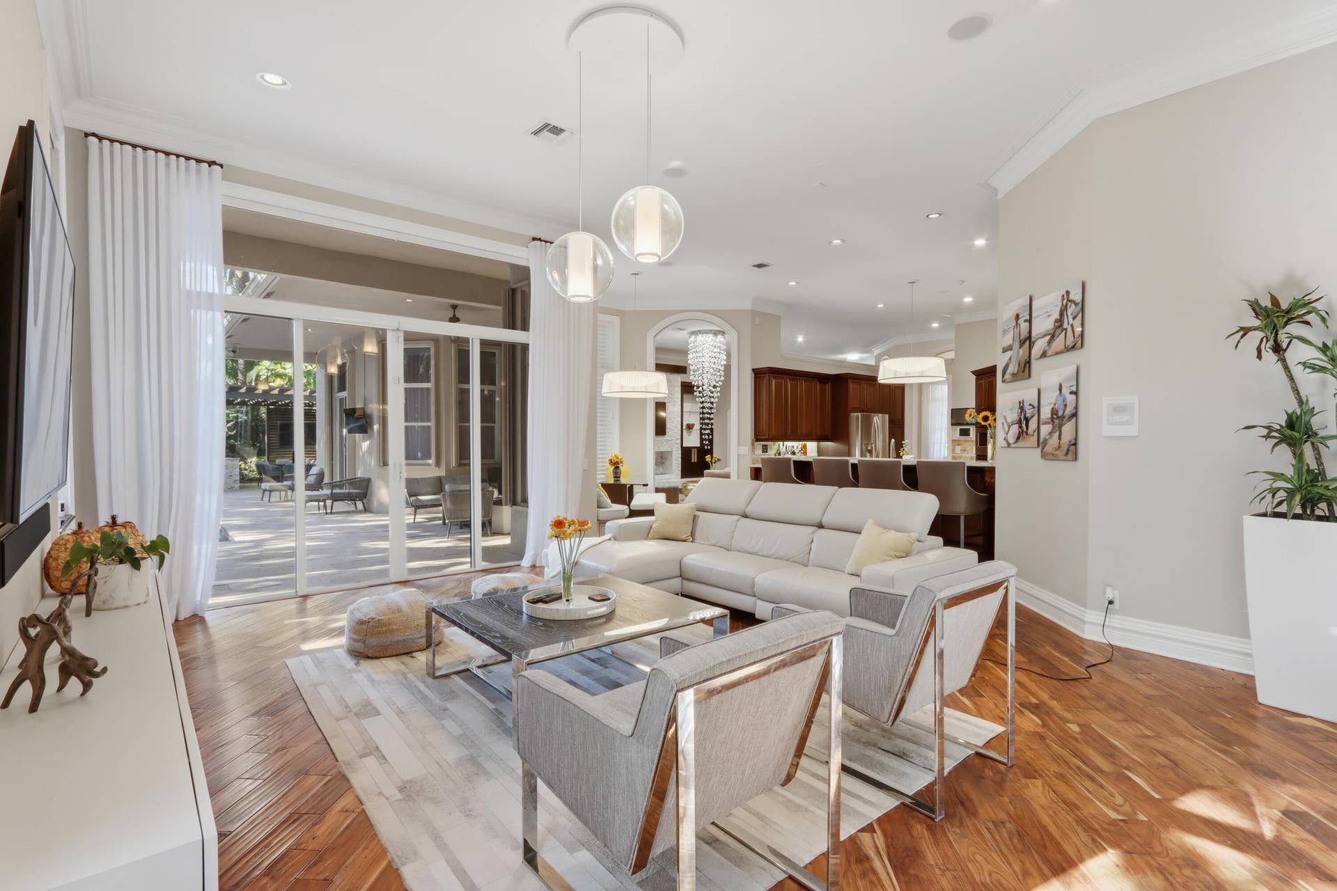 1580 VICTORIA ISLE Way, Weston, FL 33327 Open-concept living space featuring wood-finish flooring, recessed lighting, multi-pendant light fixtures, and expansive glass sliding doors