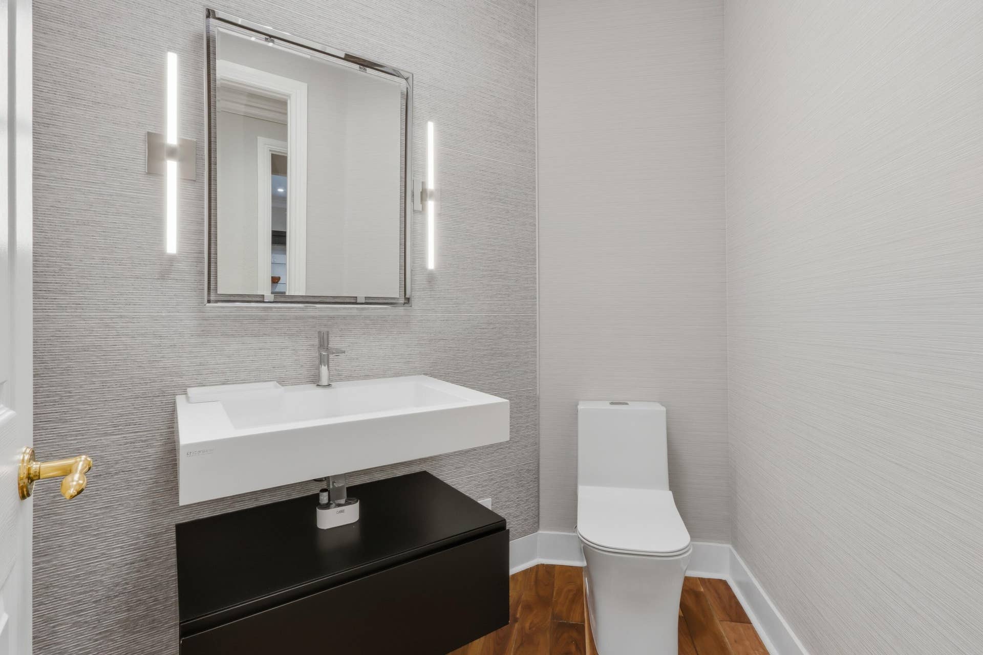 1580 VICTORIA ISLE Way, Weston, FL 33327 Wall-mounted vanity with a rectangular sink, dual vertical LED sconces, textured wall covering, and wood-finish flooring