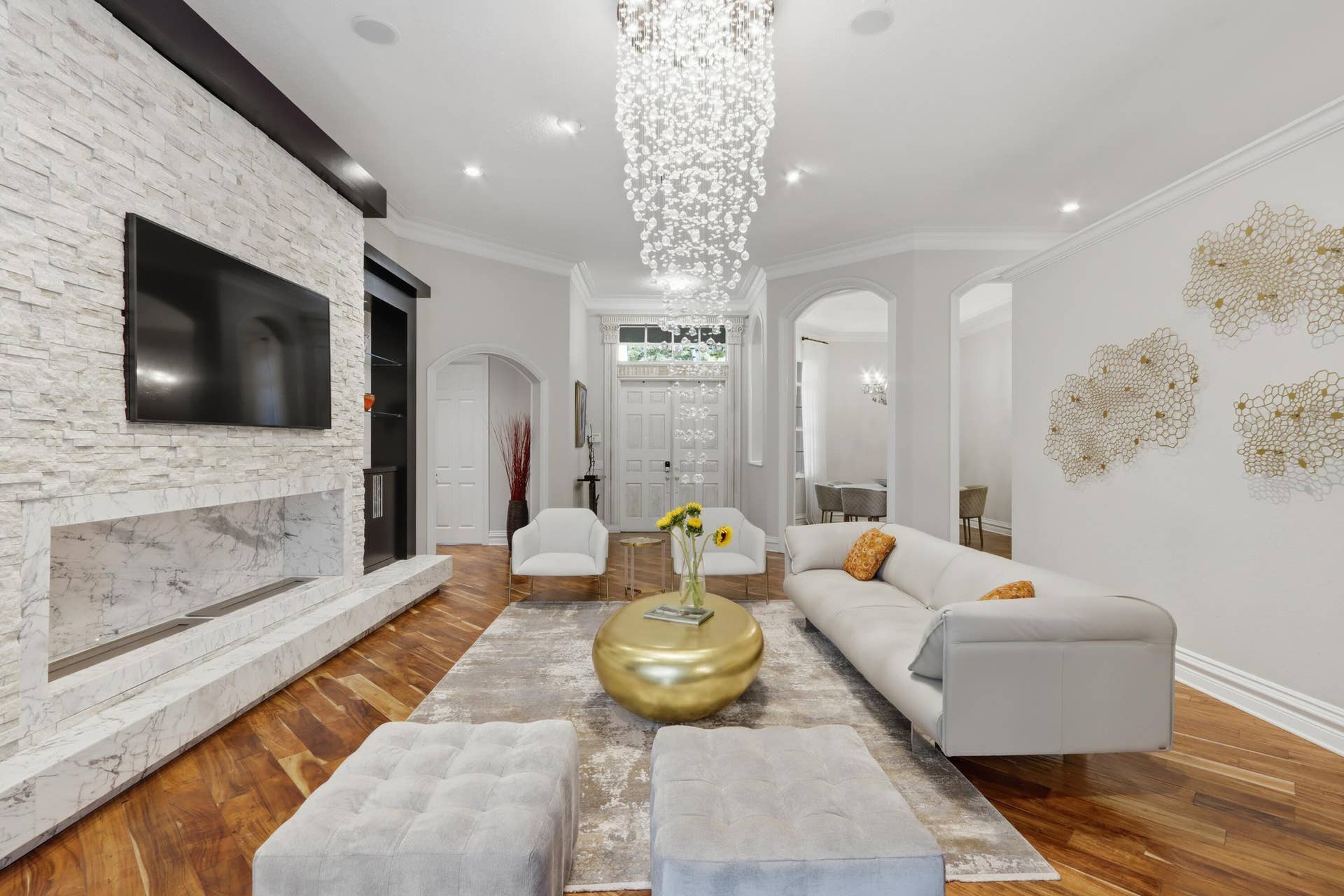 1580 VICTORIA ISLE Way, Weston, FL 33327 Formal living area featuring wood-finish flooring, a floor-to-ceiling stone-clad fireplace, a tiered crystal chandelier, and arched doorways
