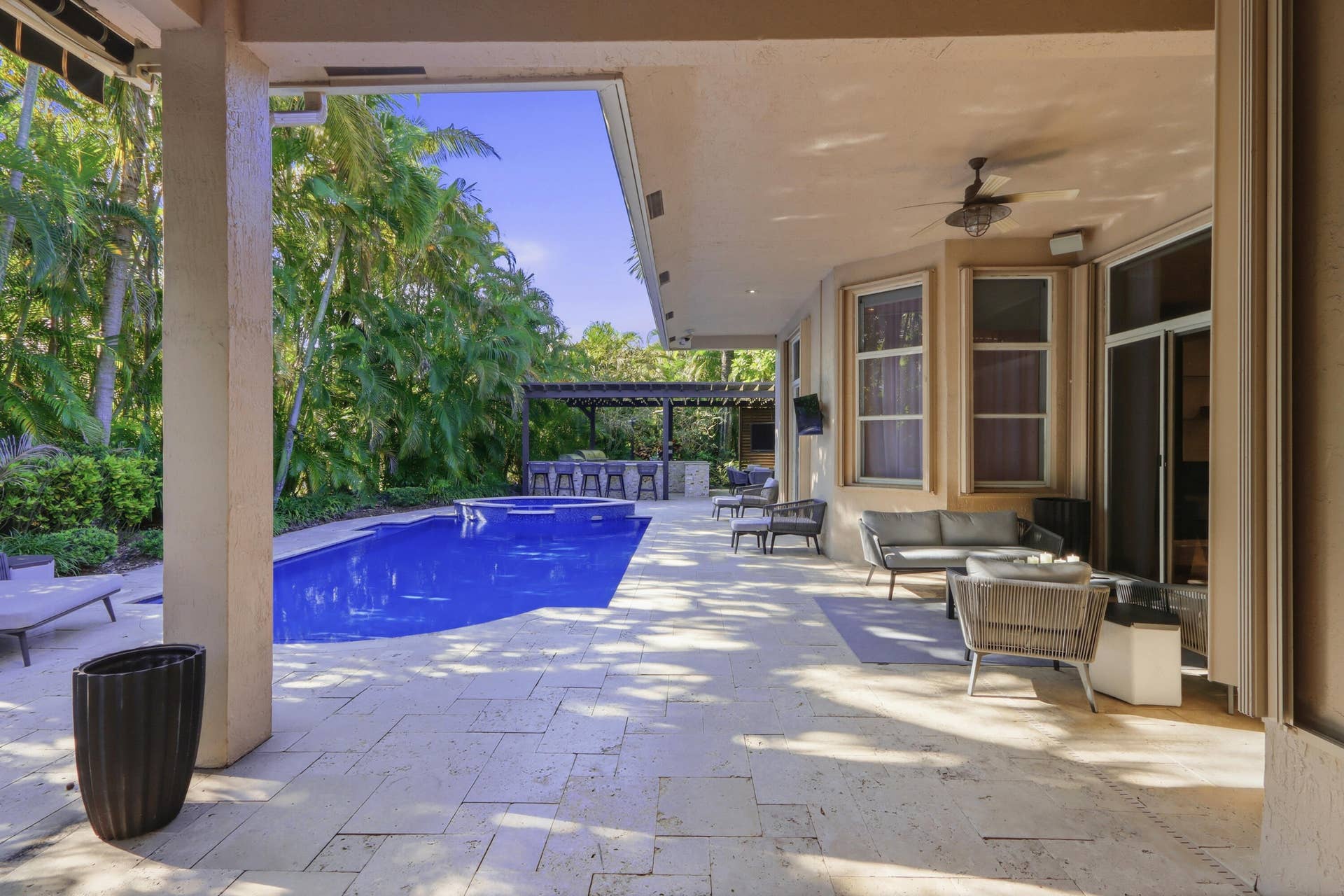 1580 VICTORIA ISLE Way, Weston, FL 33327 Covered patio featuring stone-tile flooring, a swimming pool with integrated spa, and an outdoor kitchen structure with a pergola