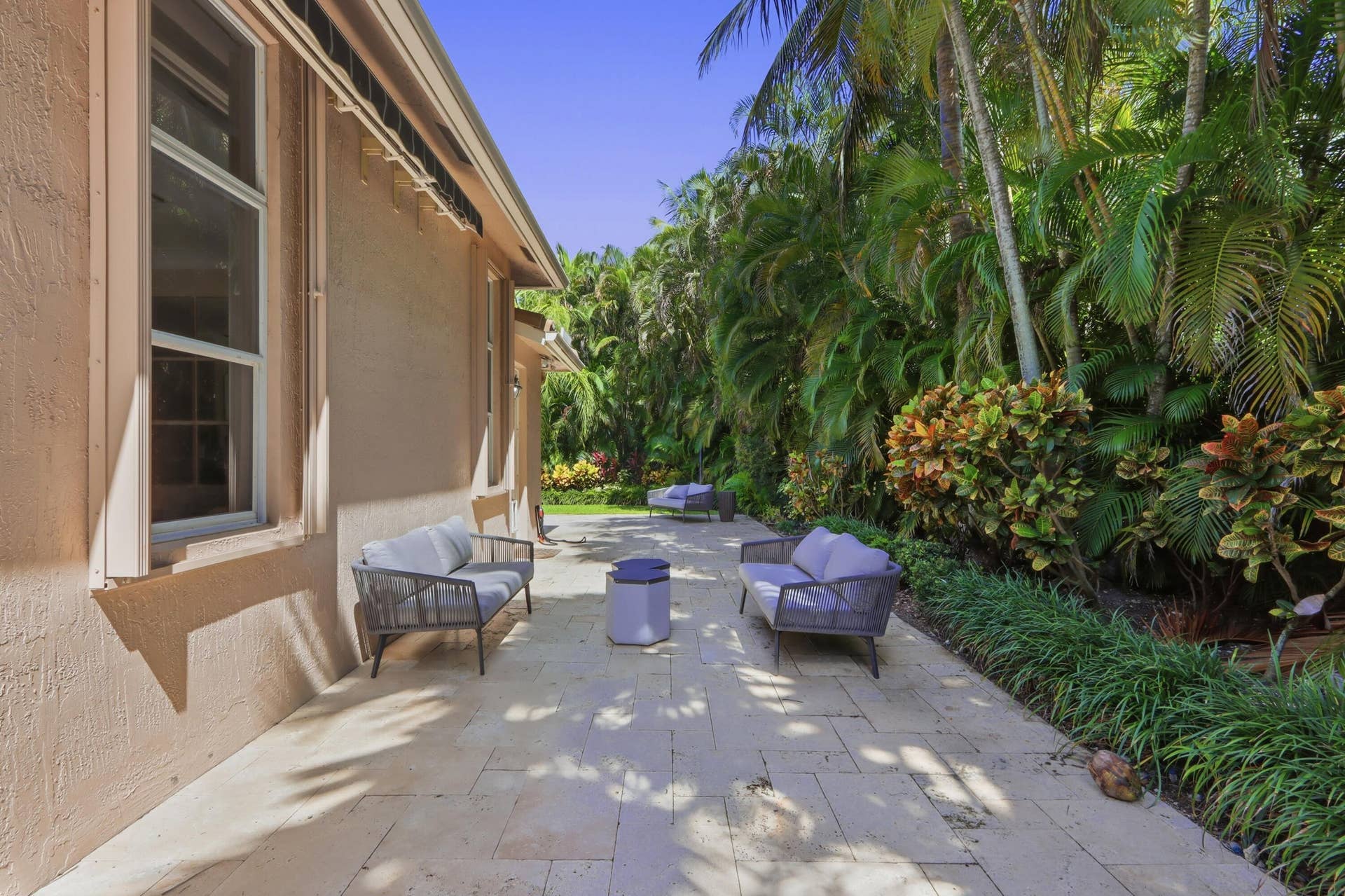 1580 VICTORIA ISLE Way, Weston, FL 33327 Paved stone patio featuring retractable awning and dense, mature tropical landscaping