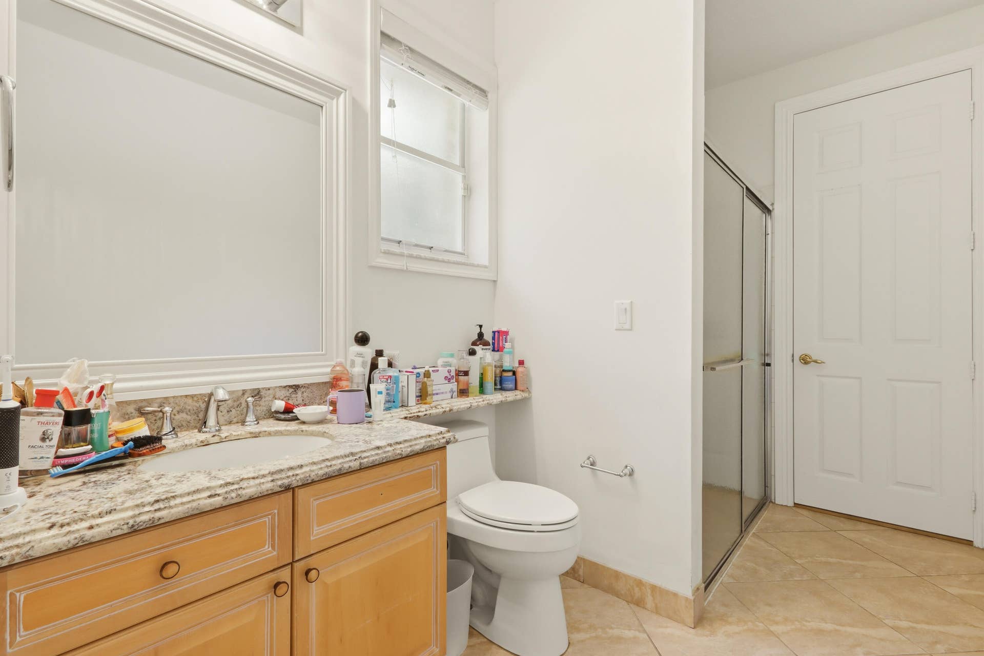 1580 VICTORIA ISLE Way, Weston, FL 33327 Bathroom featuring a wood-finish vanity with a stone-composite countertop, integrated sink, large framed mirror, and tiled flooring